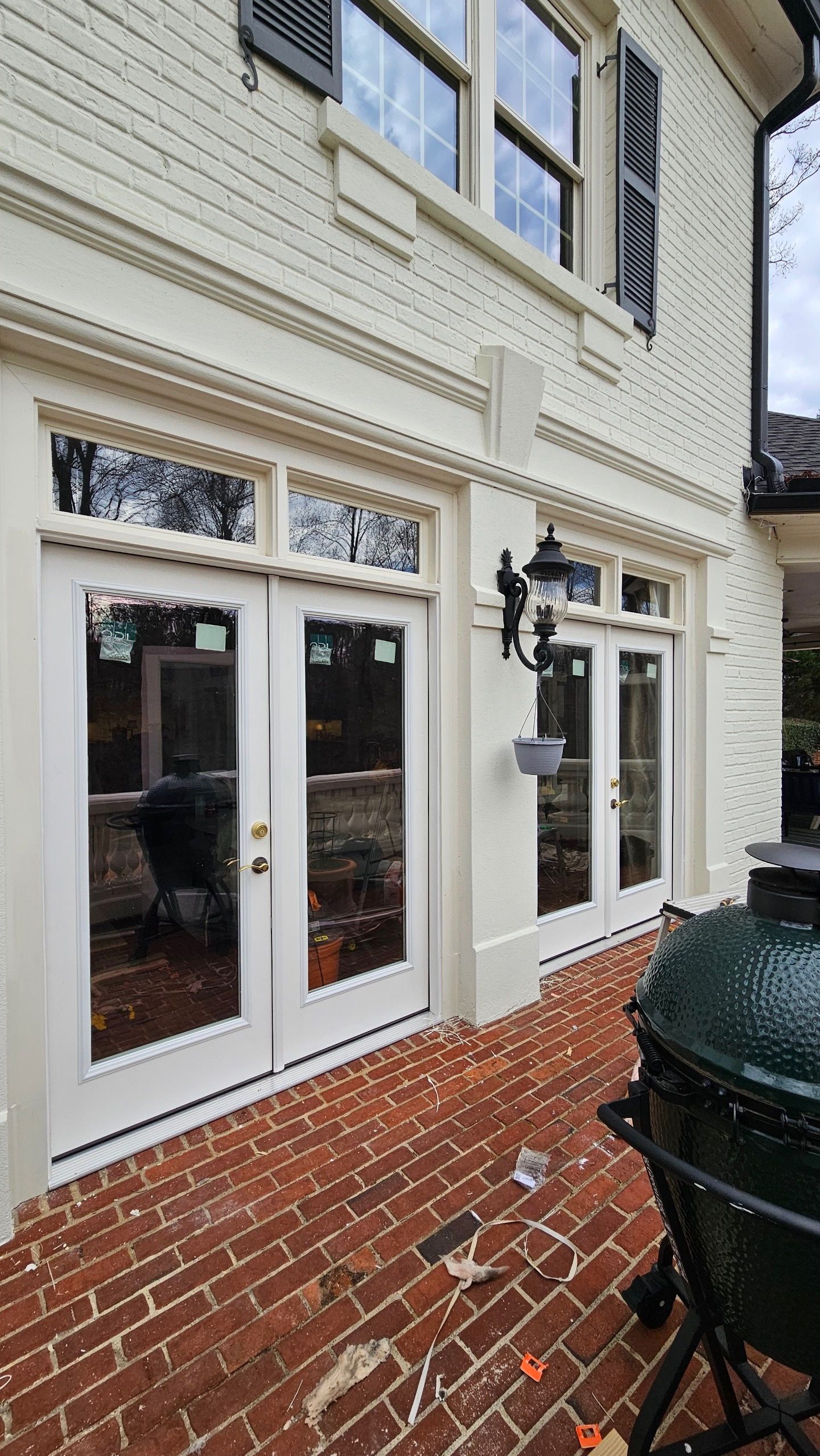 A large green egg is sitting on a brick patio next to a white house with sliding glass doors.