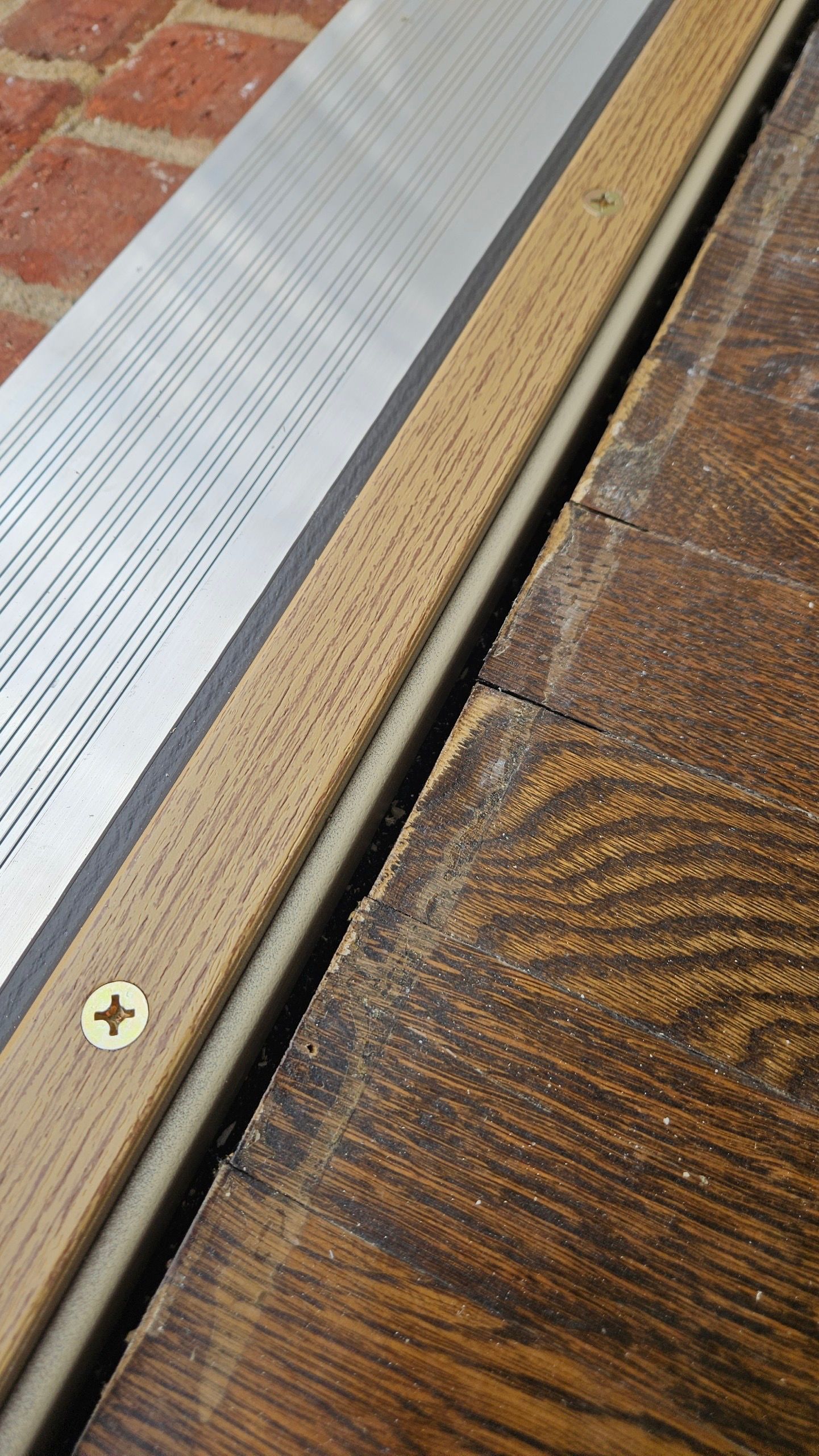 A close up of a door sill on a wooden floor.