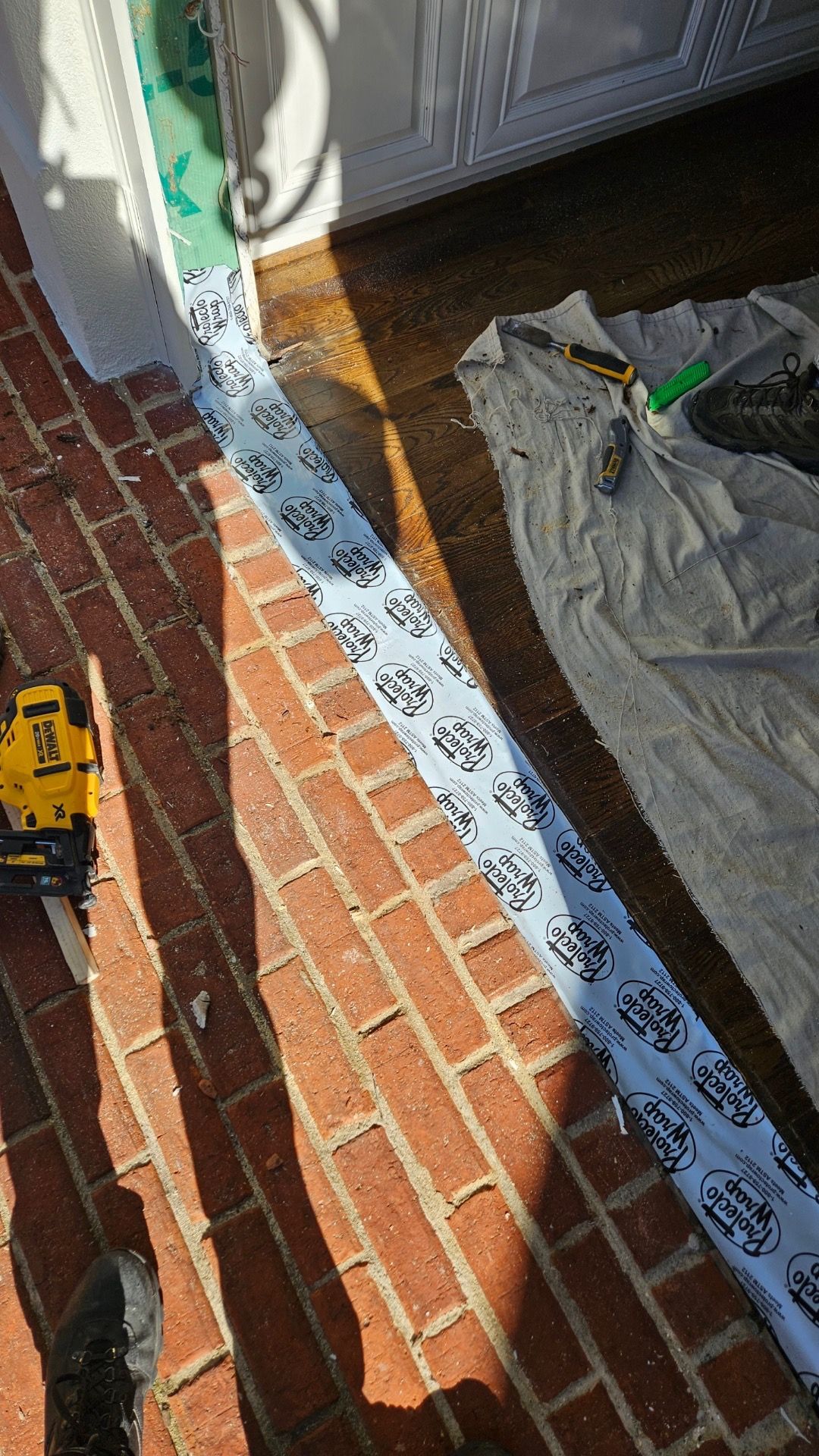 A person is cutting a piece of tape on a brick floor.