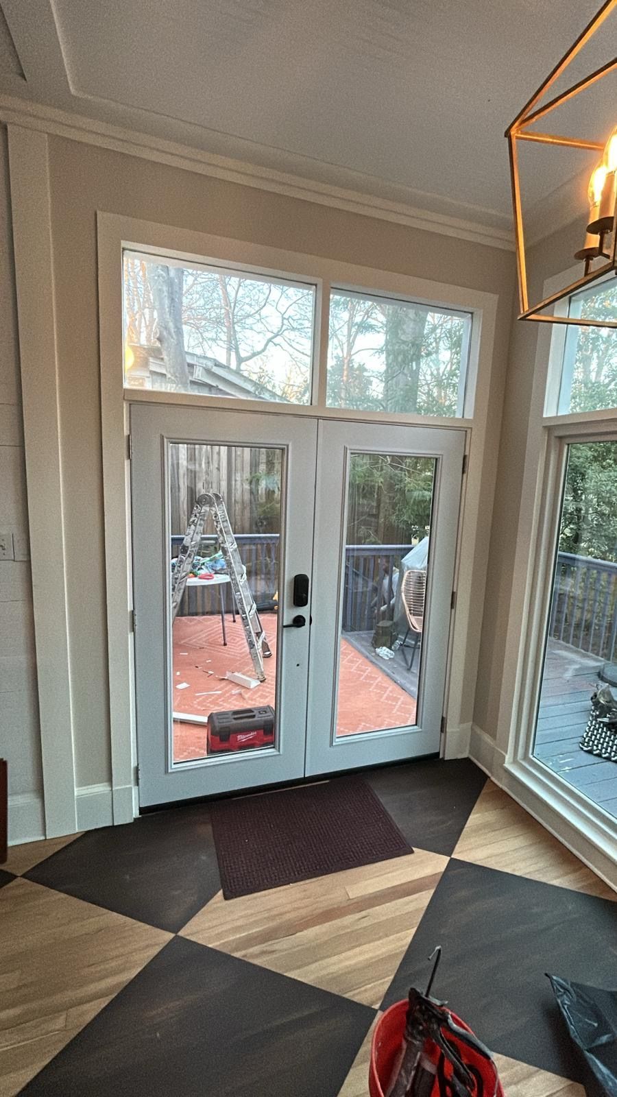 A room with a checkered floor , a ladder , a door and a window.