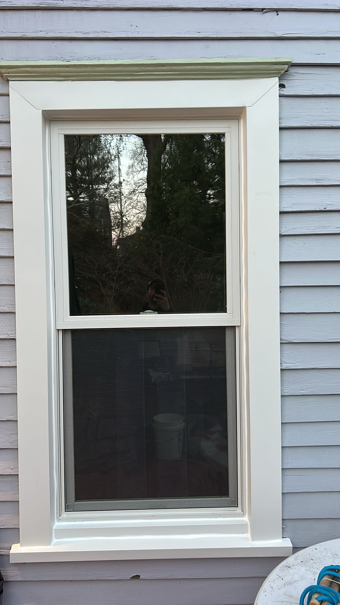 A white window is on the side of a house.