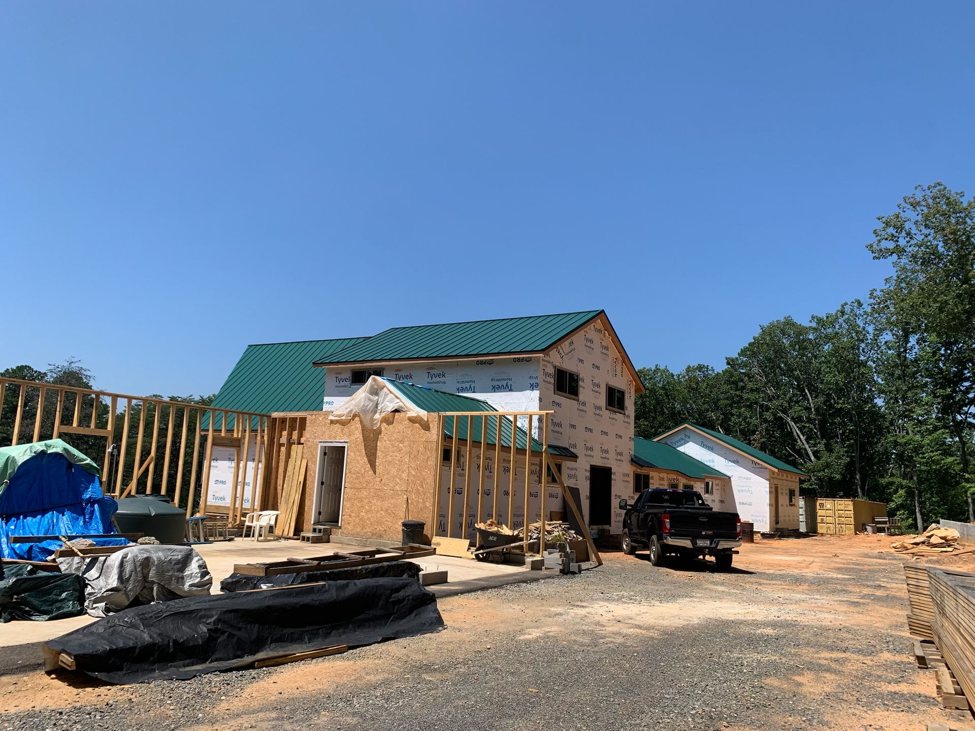 A house under construction with a green roof and a truck parked in front of it.