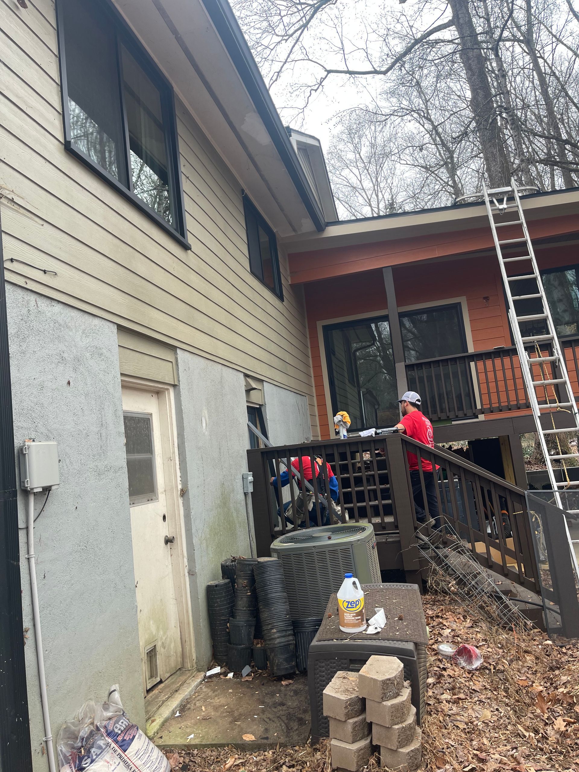 A man is standing on a ladder in front of a house.