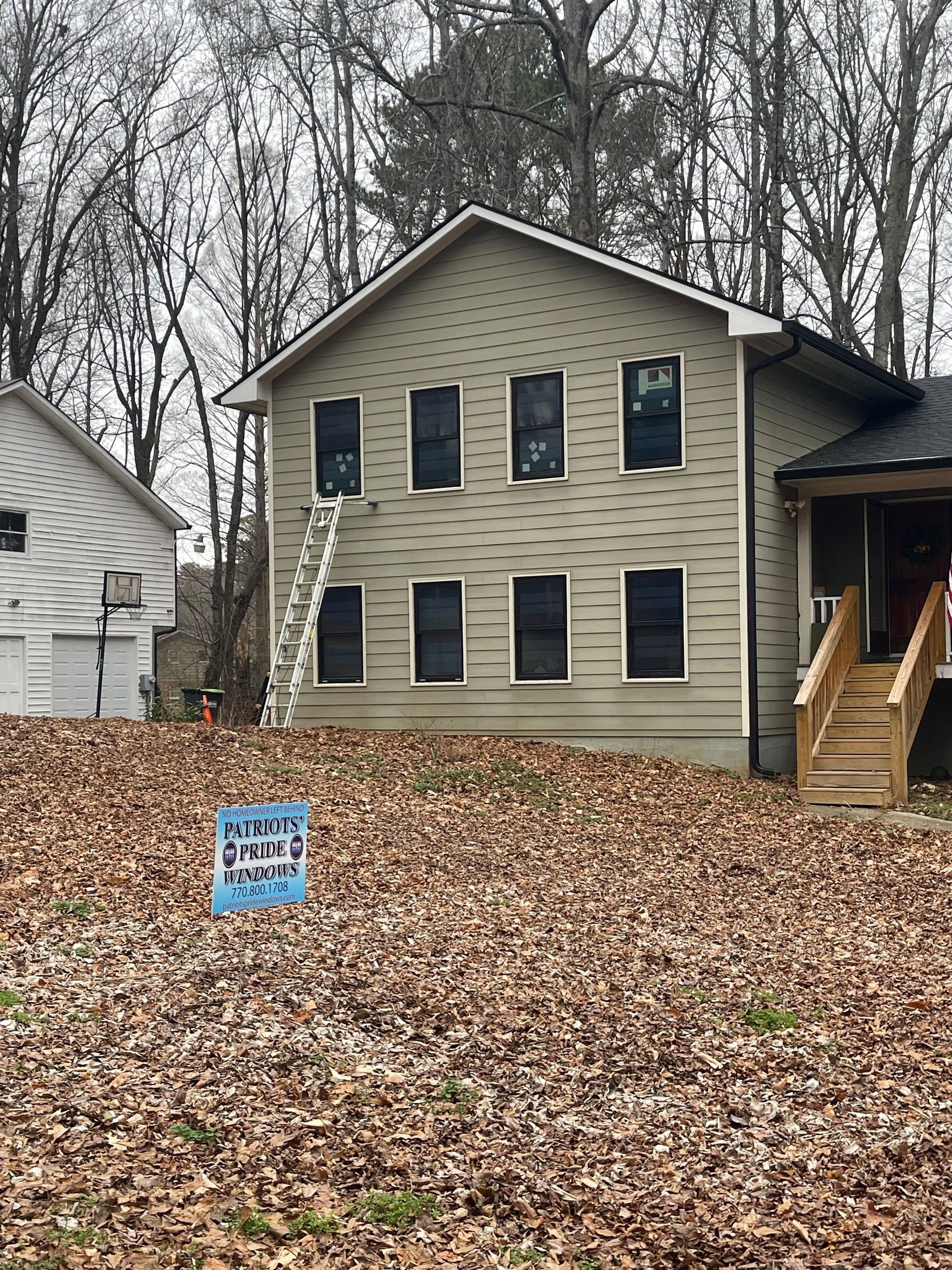 A house with a sign in front of it and a lot of leaves on the ground.