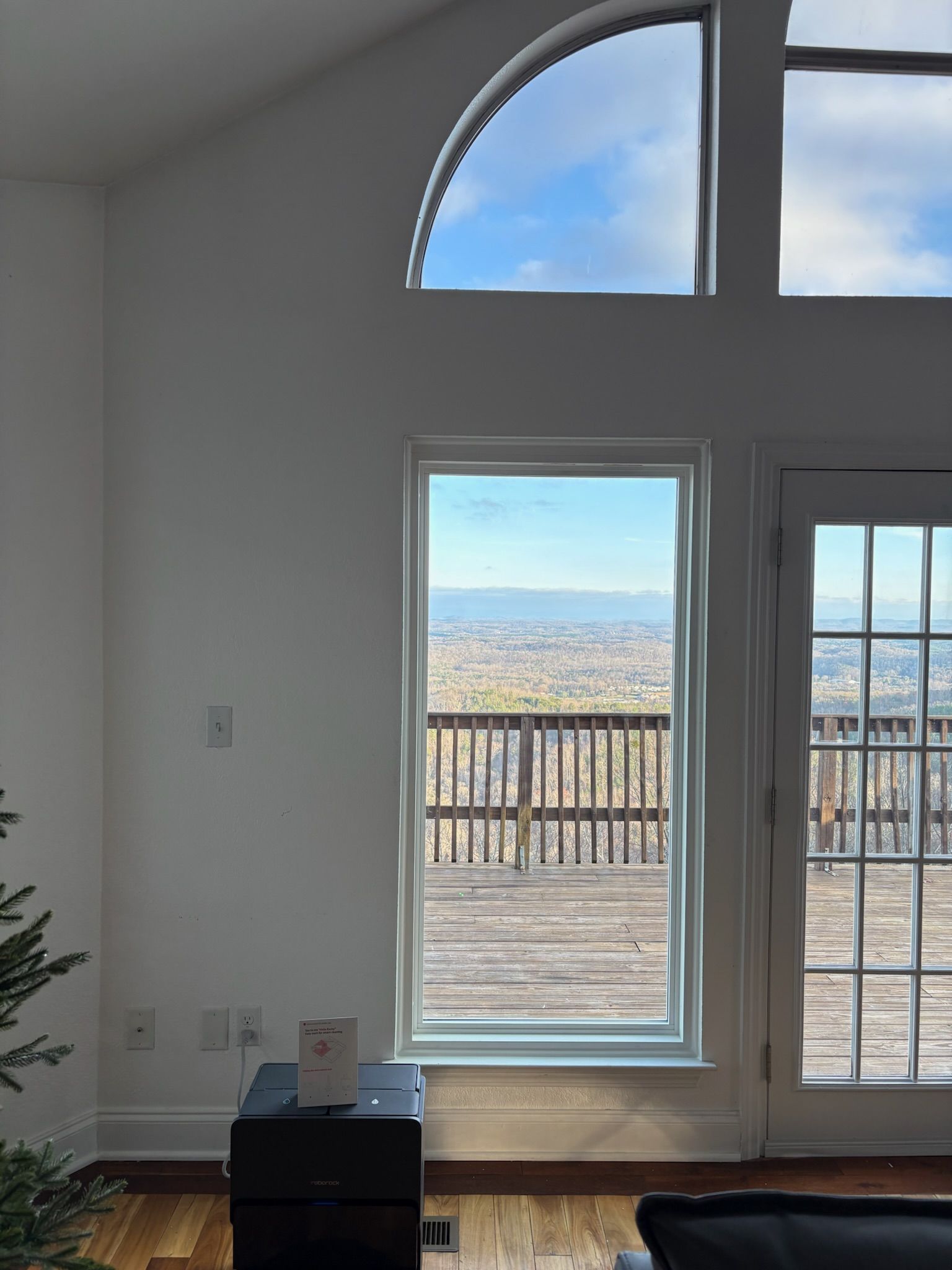 A living room with a large window and a christmas tree