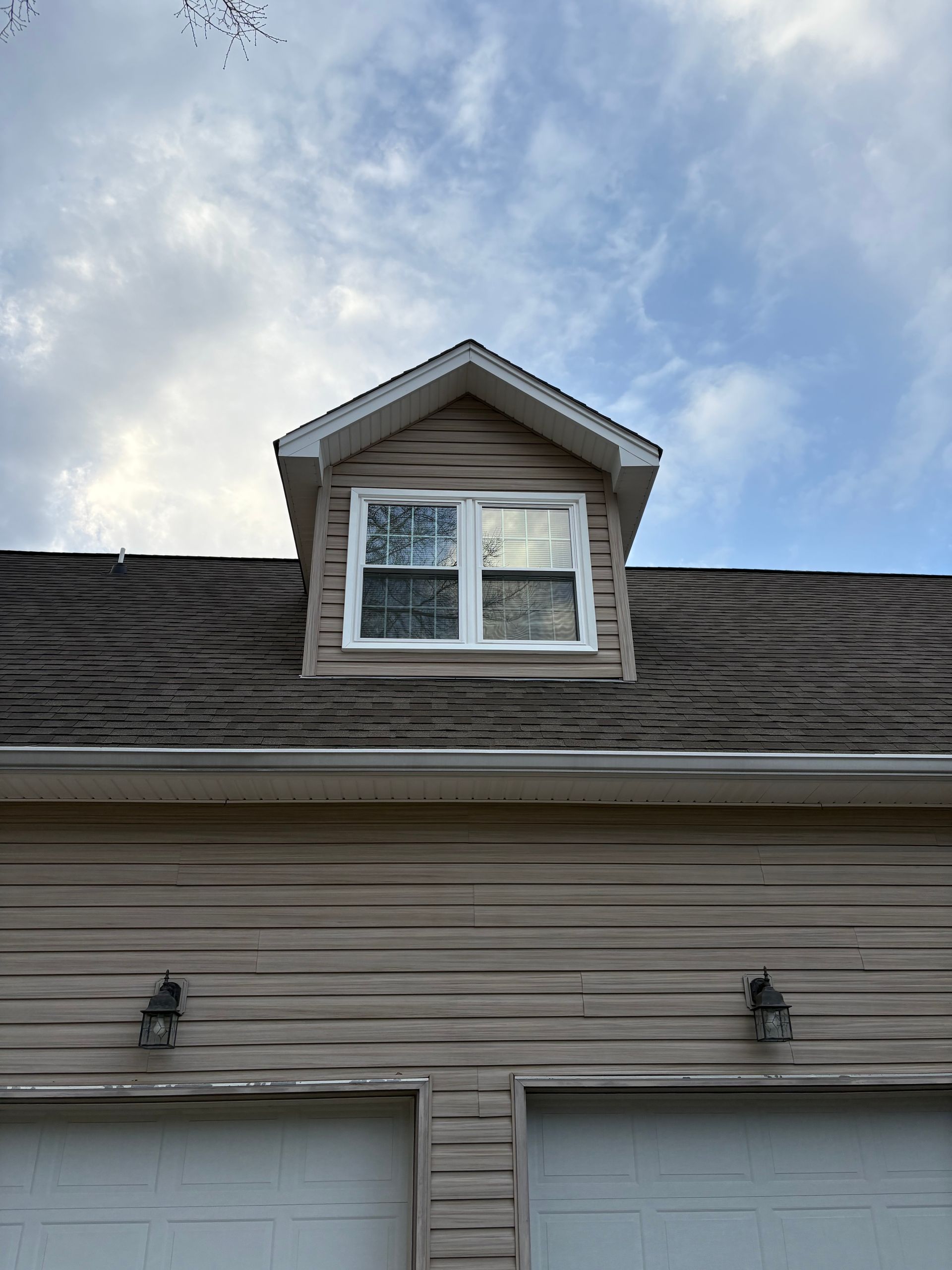 A house with two garage doors and a window on the roof.
