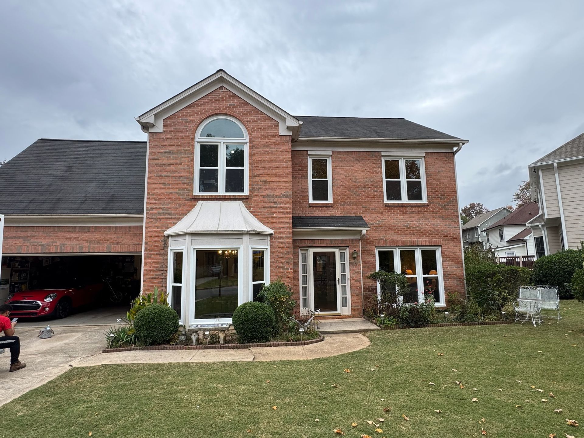 A large brick house with a red car parked in the driveway.