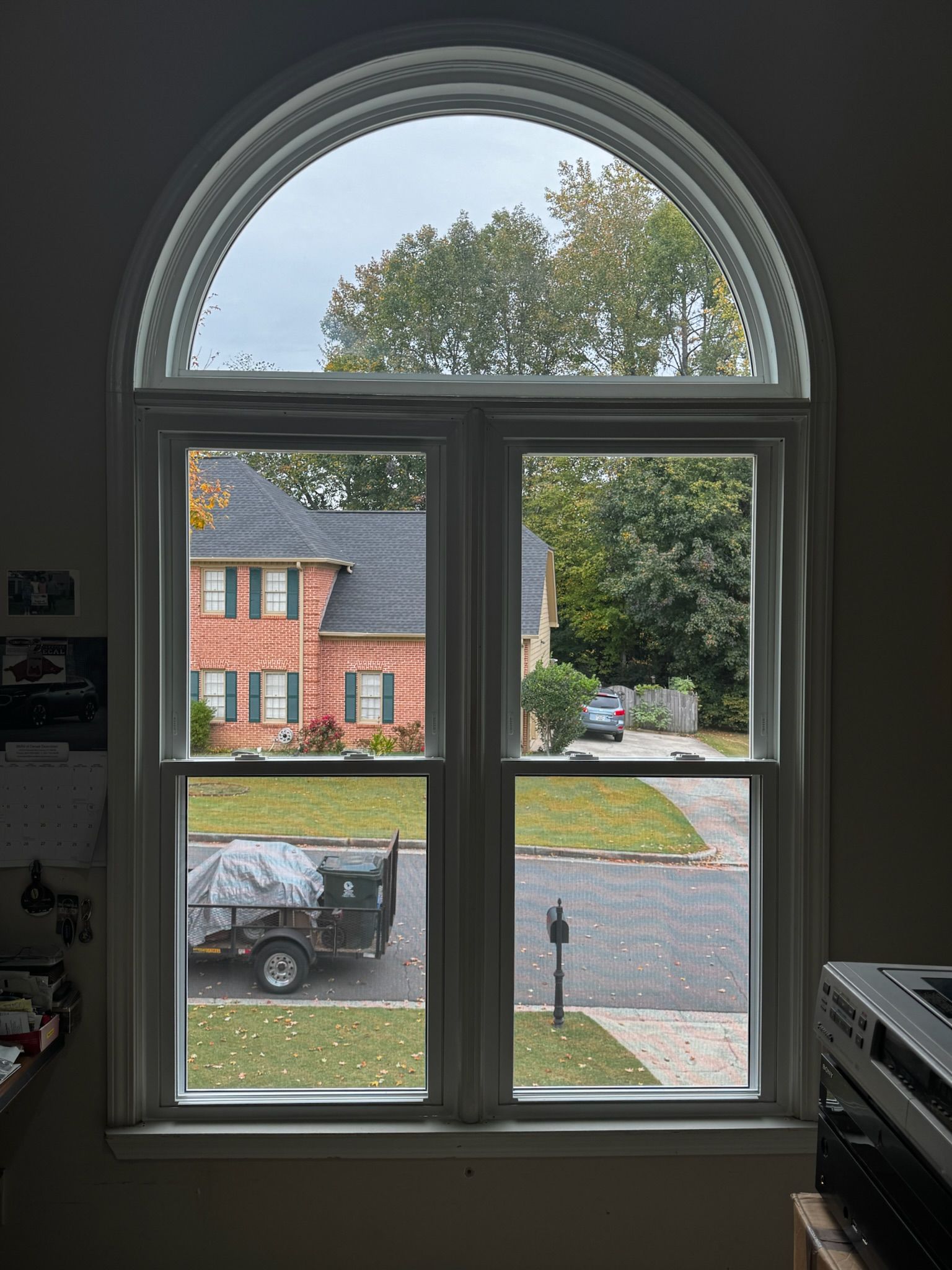 A window with a view of a brick house and a truck parked in front of it.