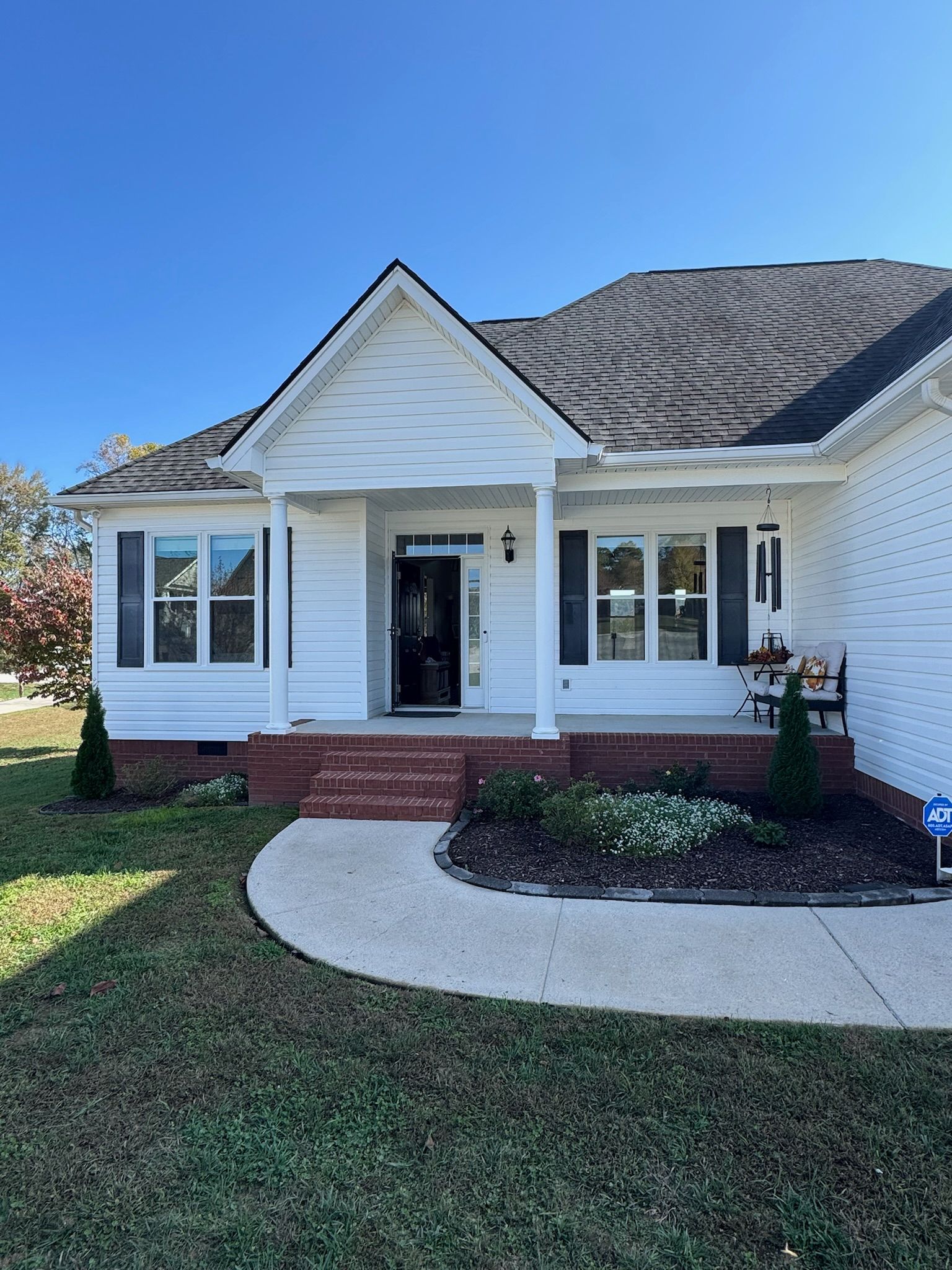 A white house with a brick porch and a blue sky in the background.