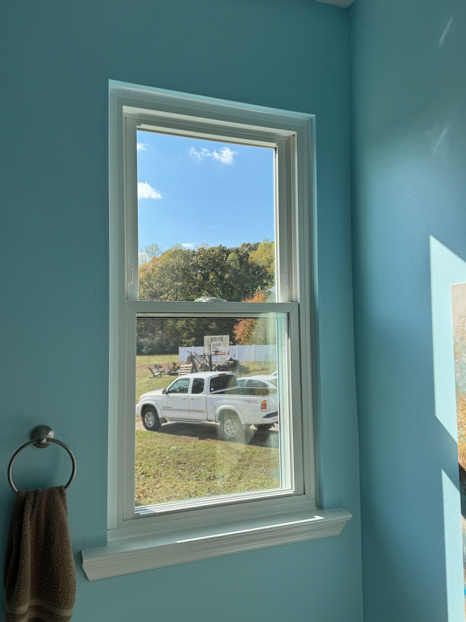 A white truck is parked in front of a window in a bathroom.