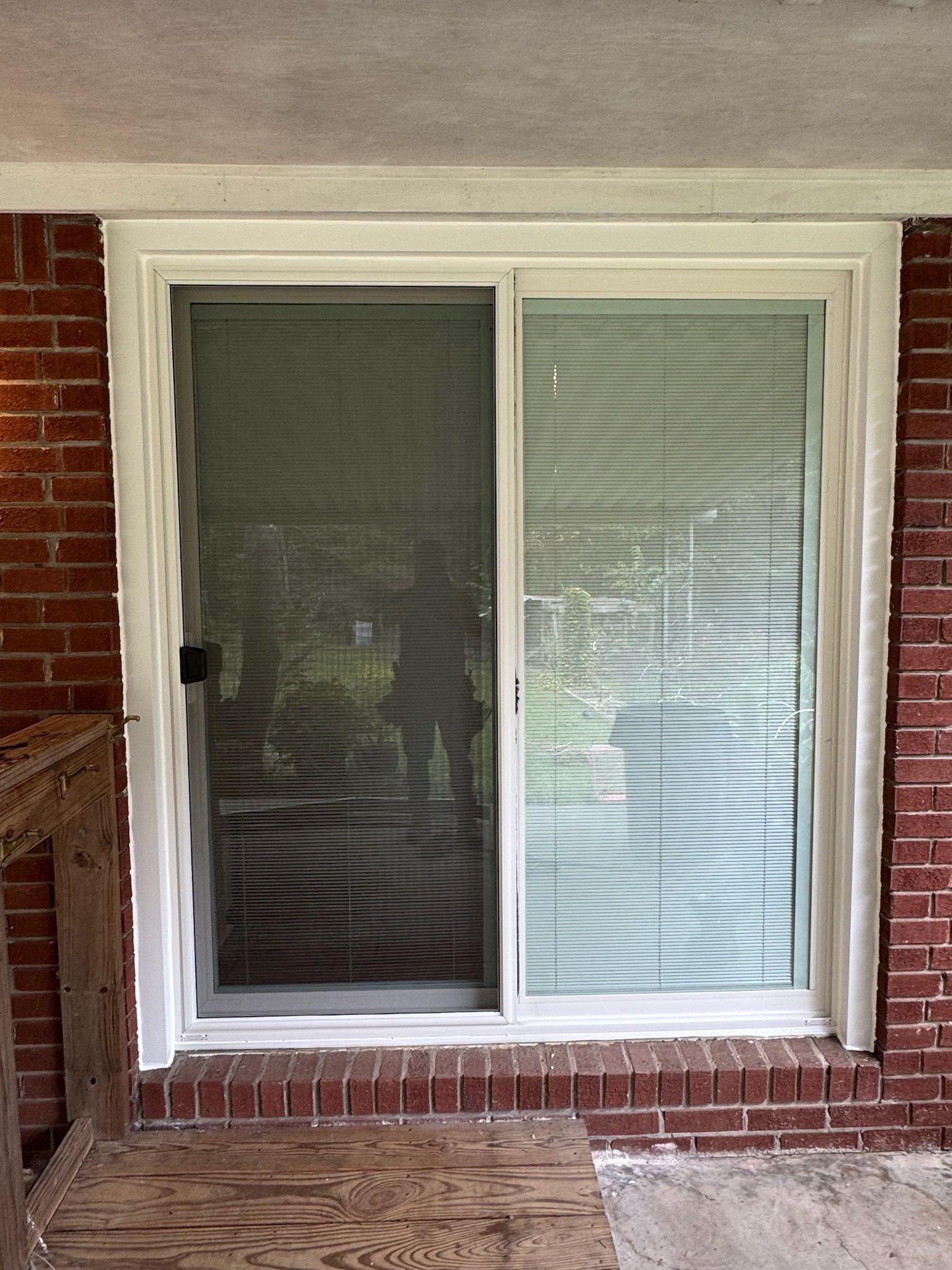A sliding glass door with blinds on a brick wall