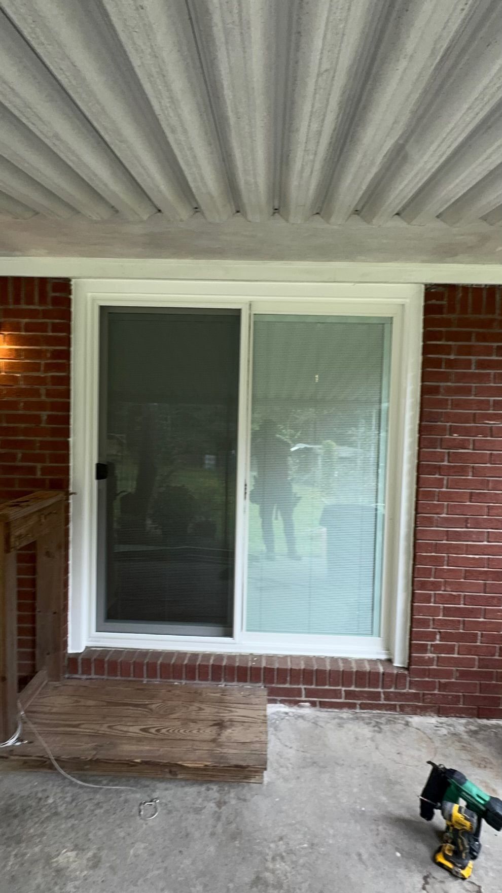 A sliding glass door is being installed on a brick house.