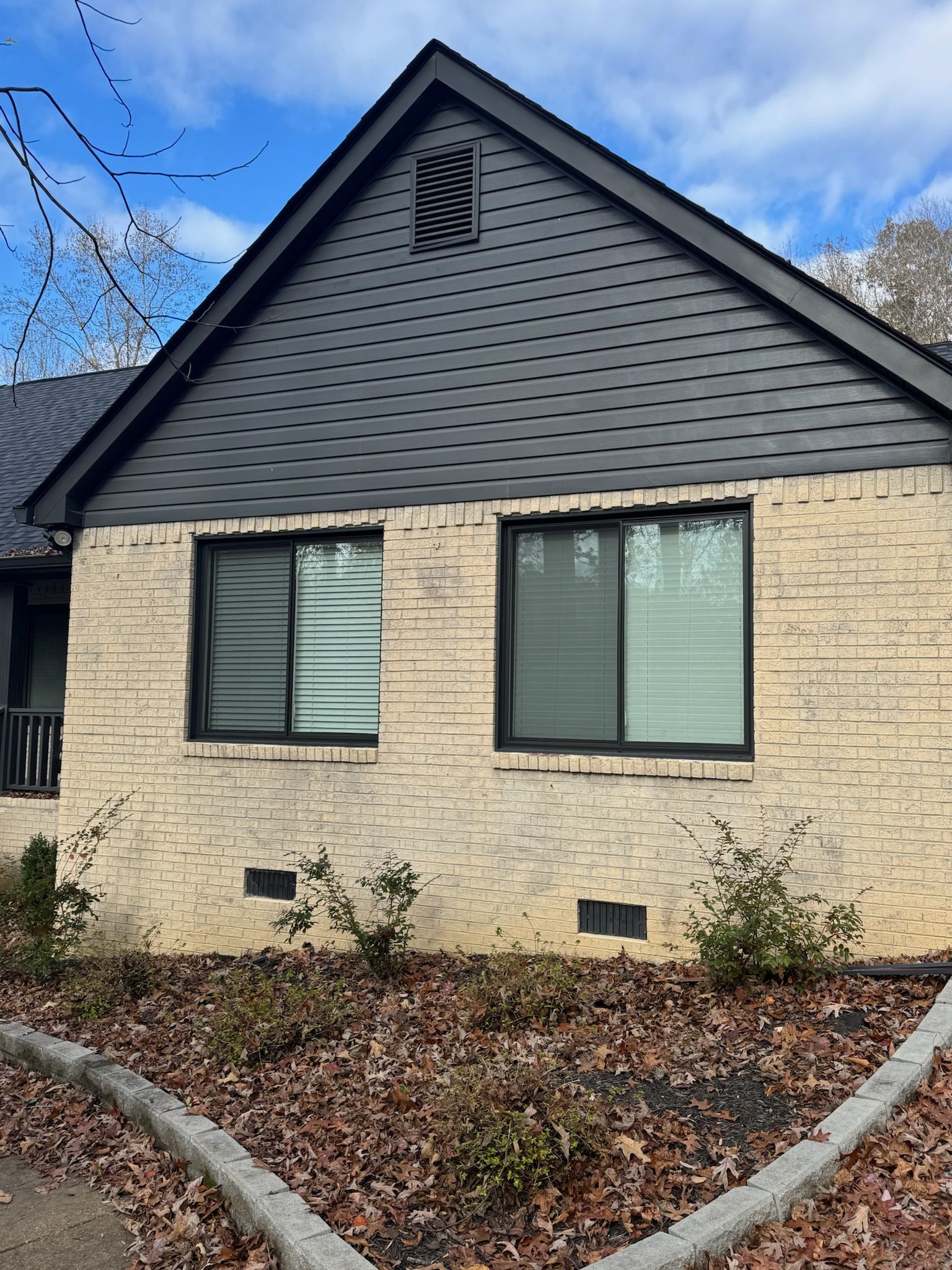 A white brick house with a black roof and windows.