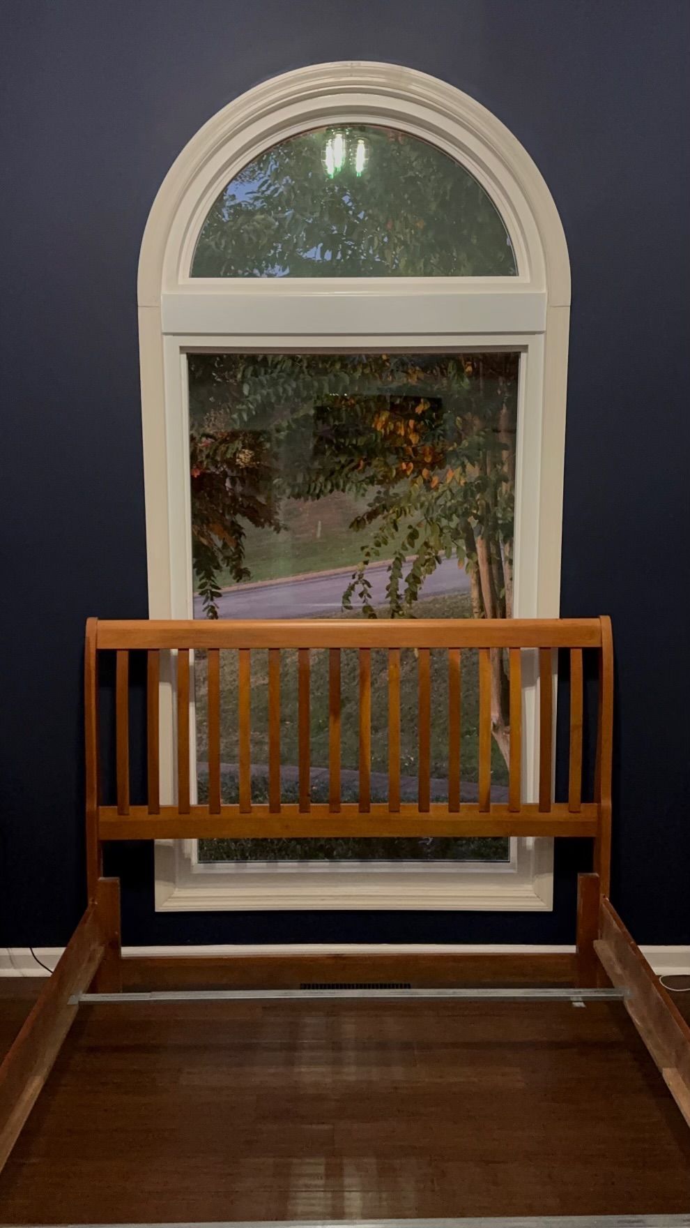 A wooden bench is sitting in front of a window.