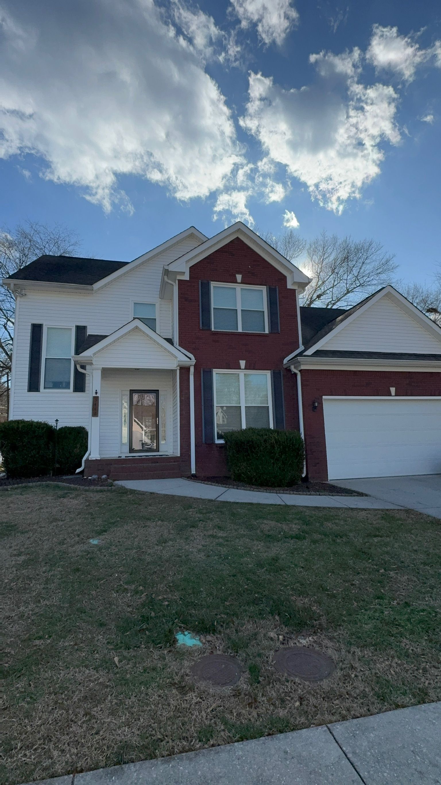 A large red brick house with a white garage door is for sale.