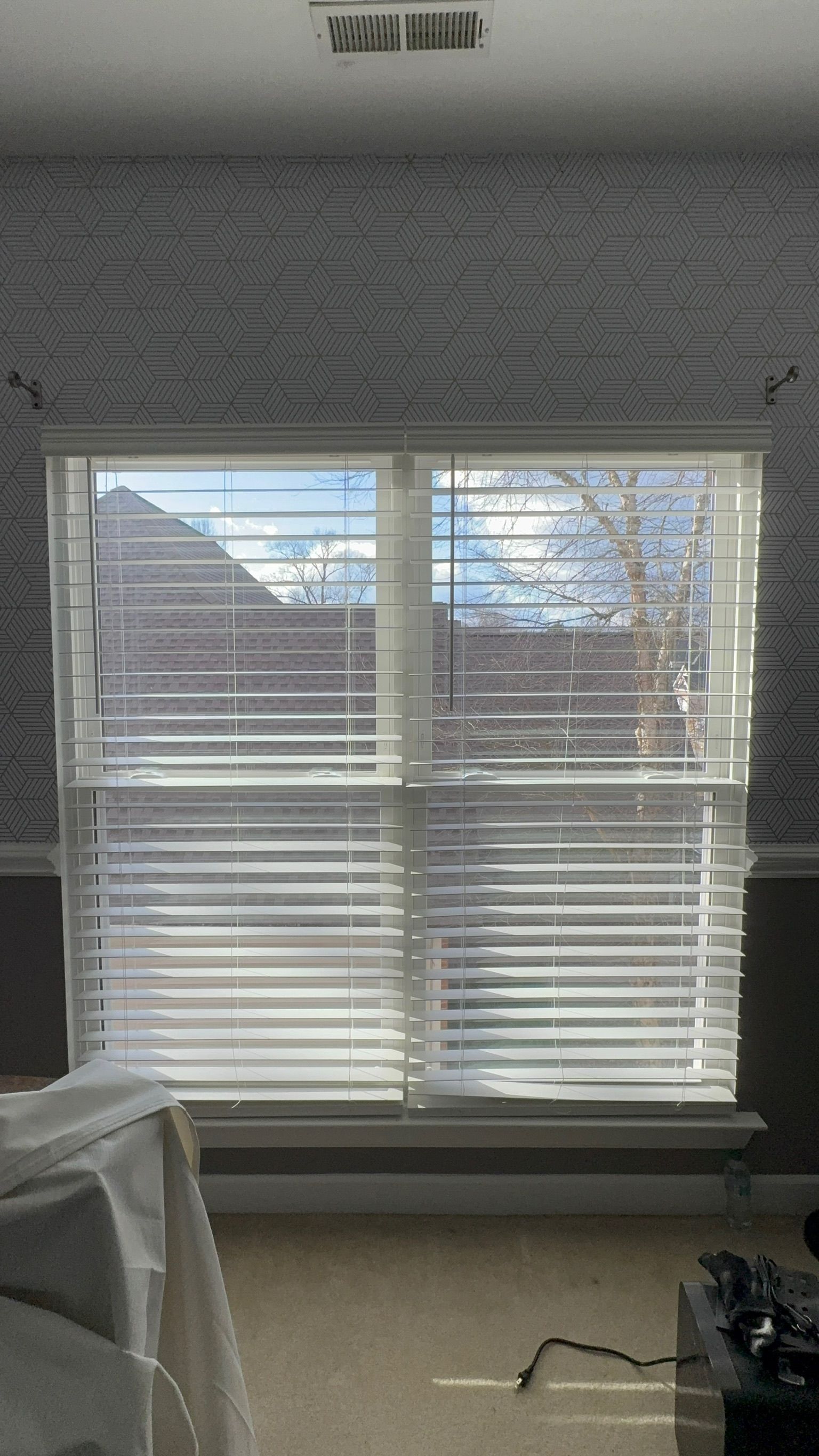 A bedroom with a large window with blinds on it.