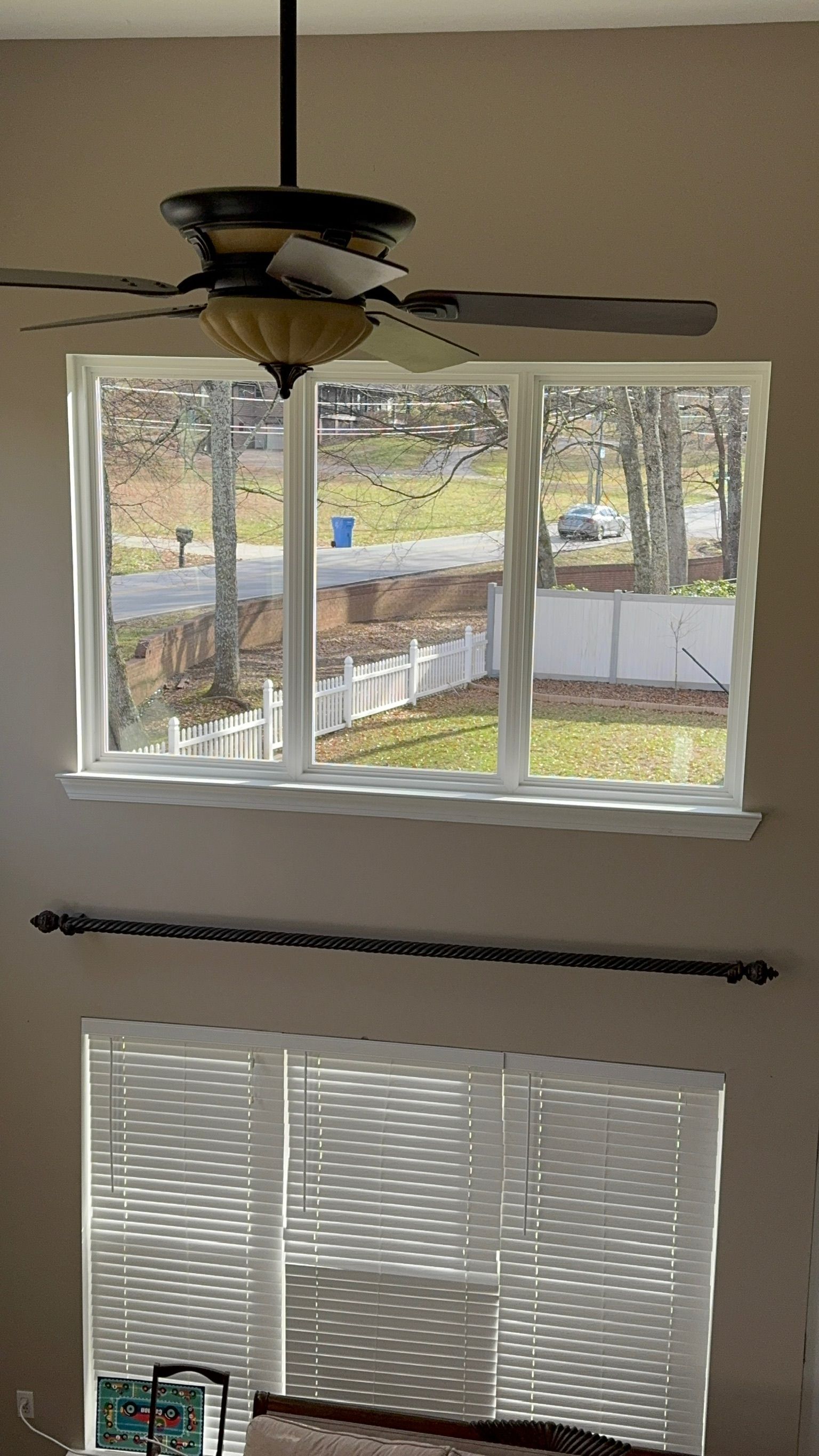 A living room with a large window and a ceiling fan.