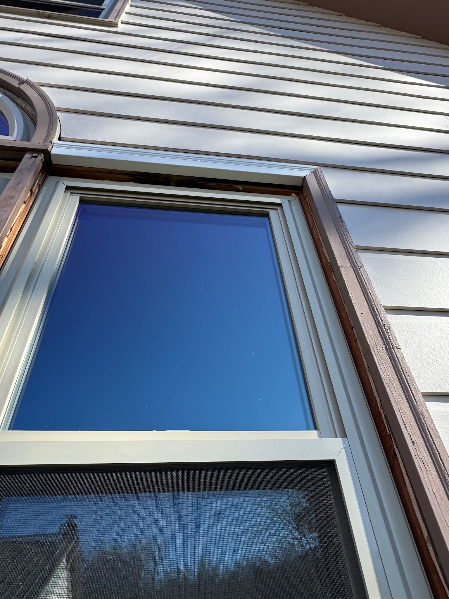 A window with a screen on it is on the side of a house.