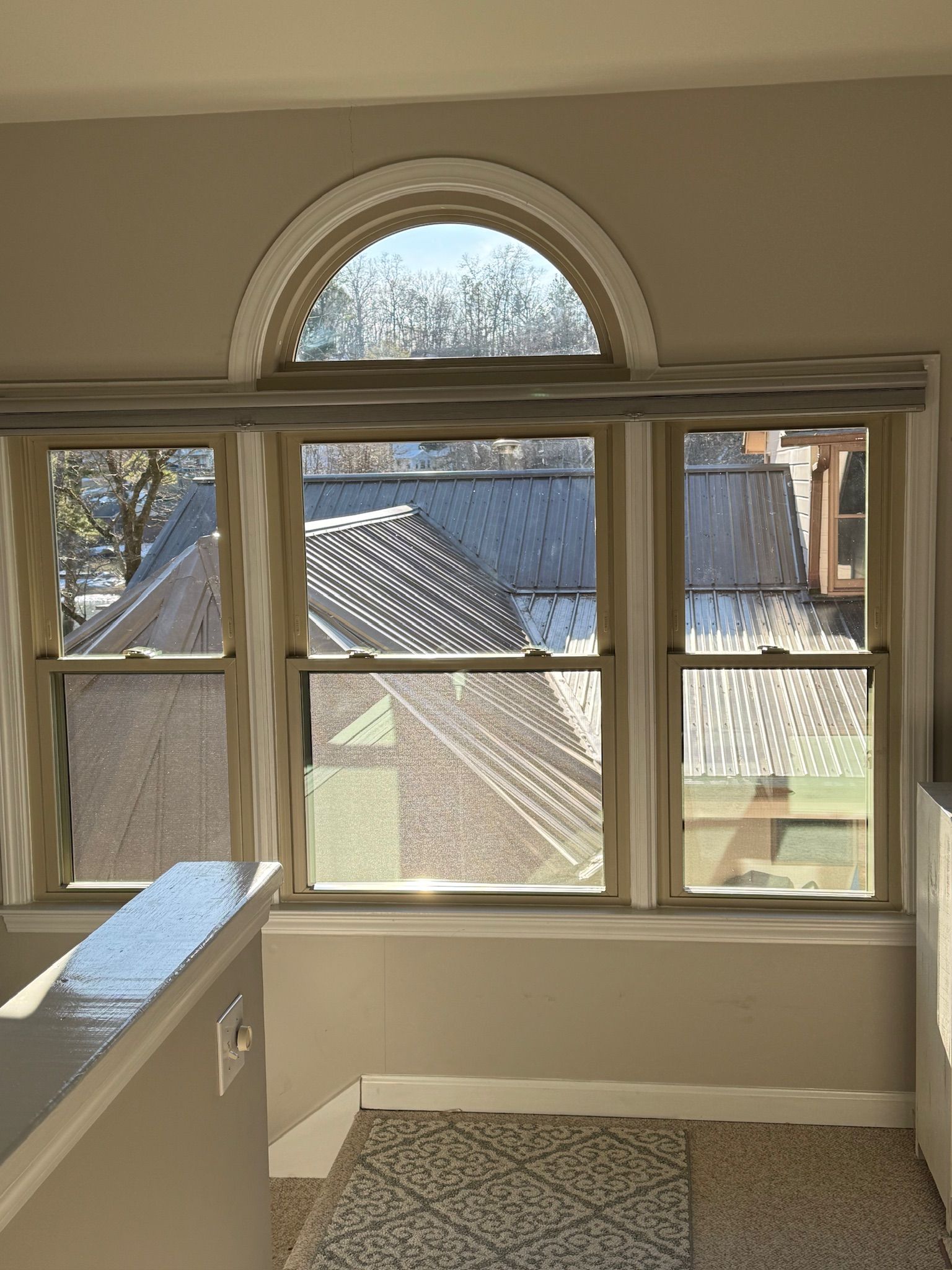 There are three windows in the room with a view of the roof.