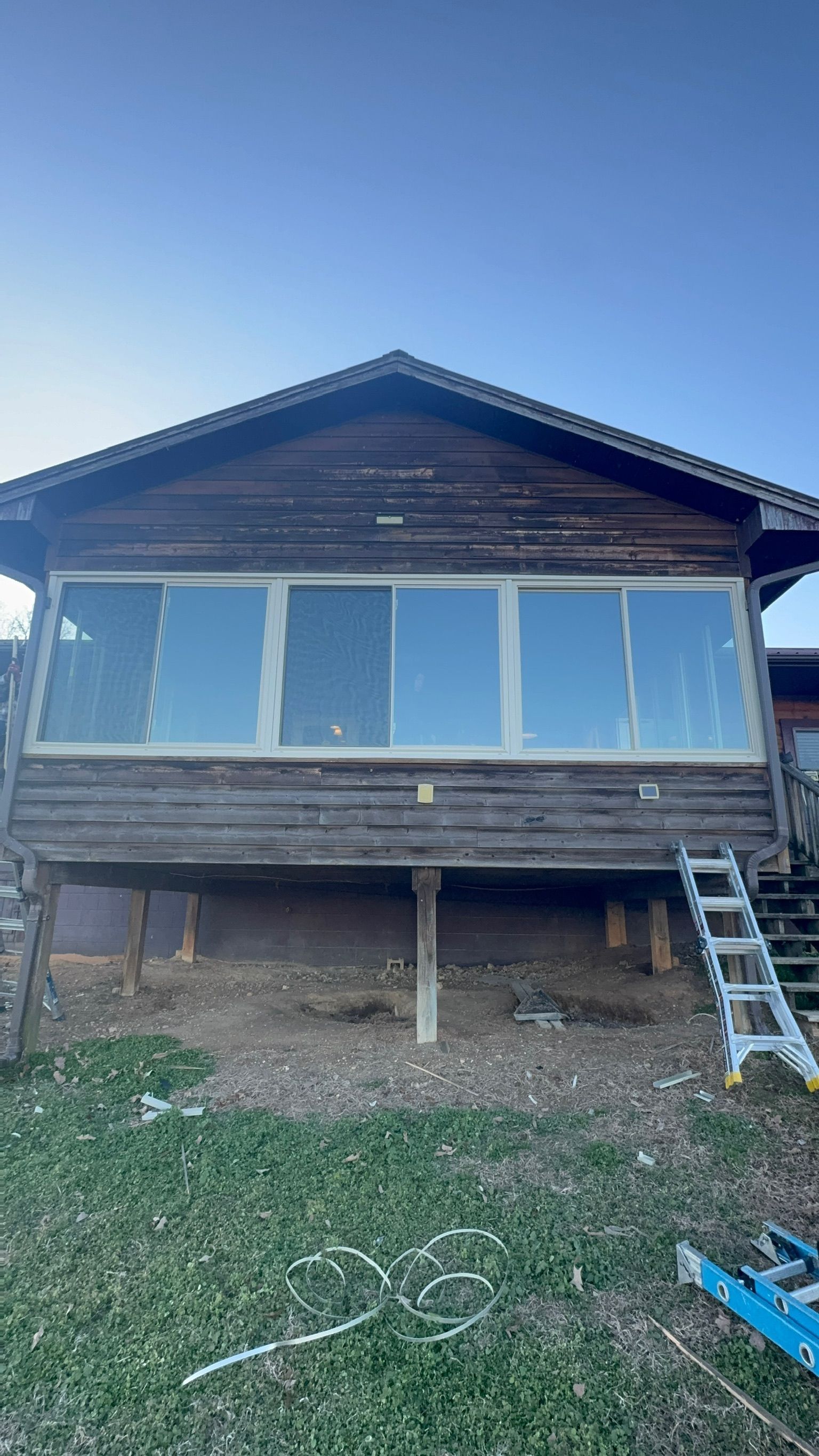 A large wooden house with a lot of windows and a ladder in front of it.