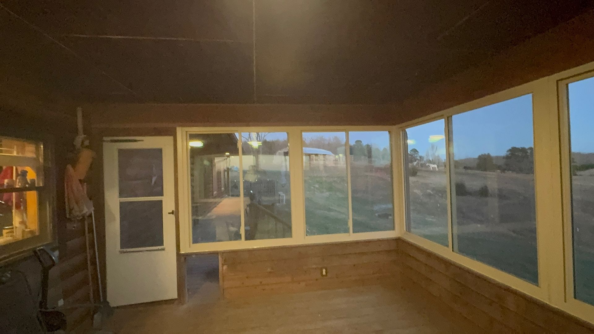 A screened in porch with a lot of windows and a door.
