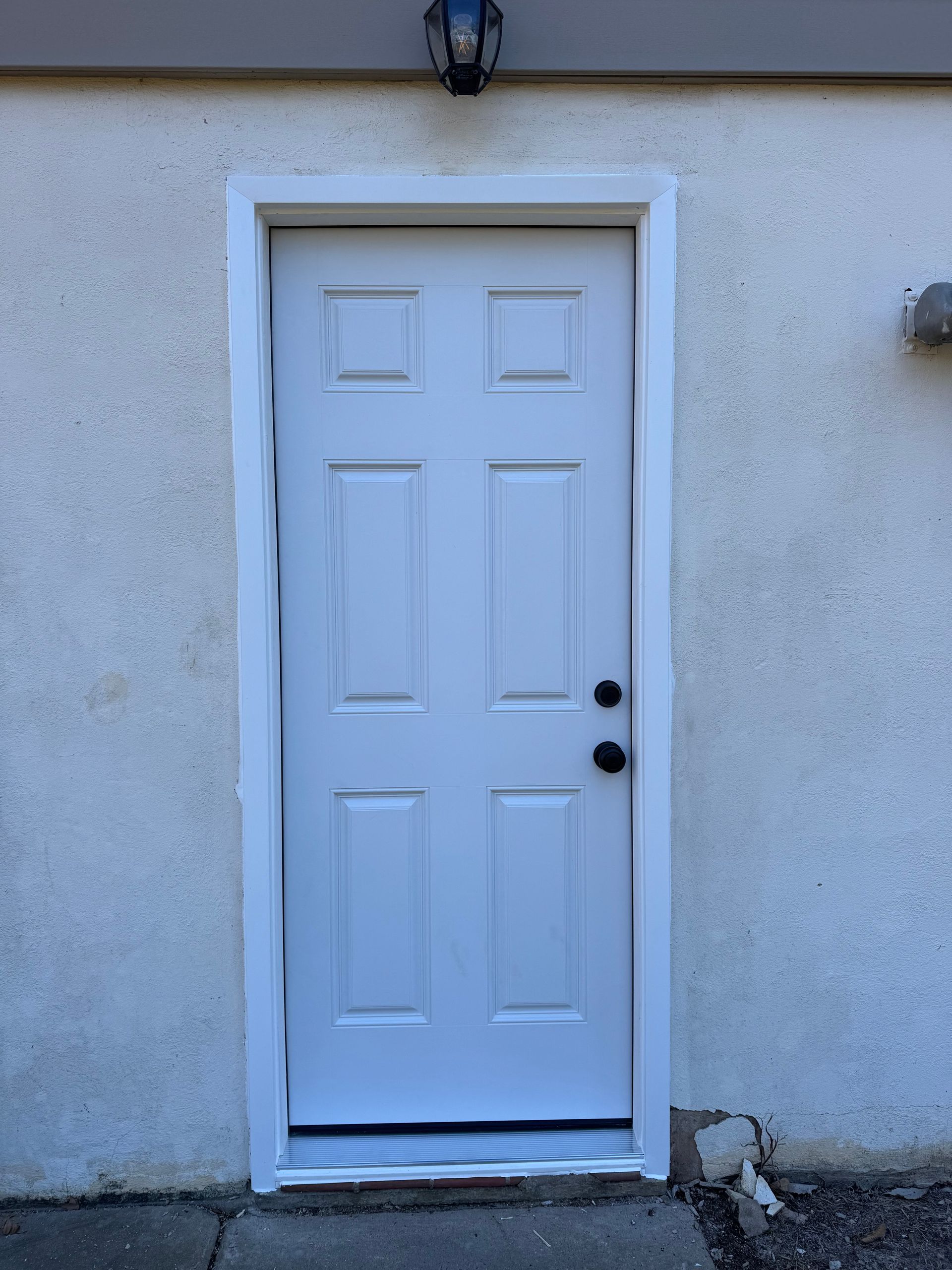 A white door is sitting on the side of a building