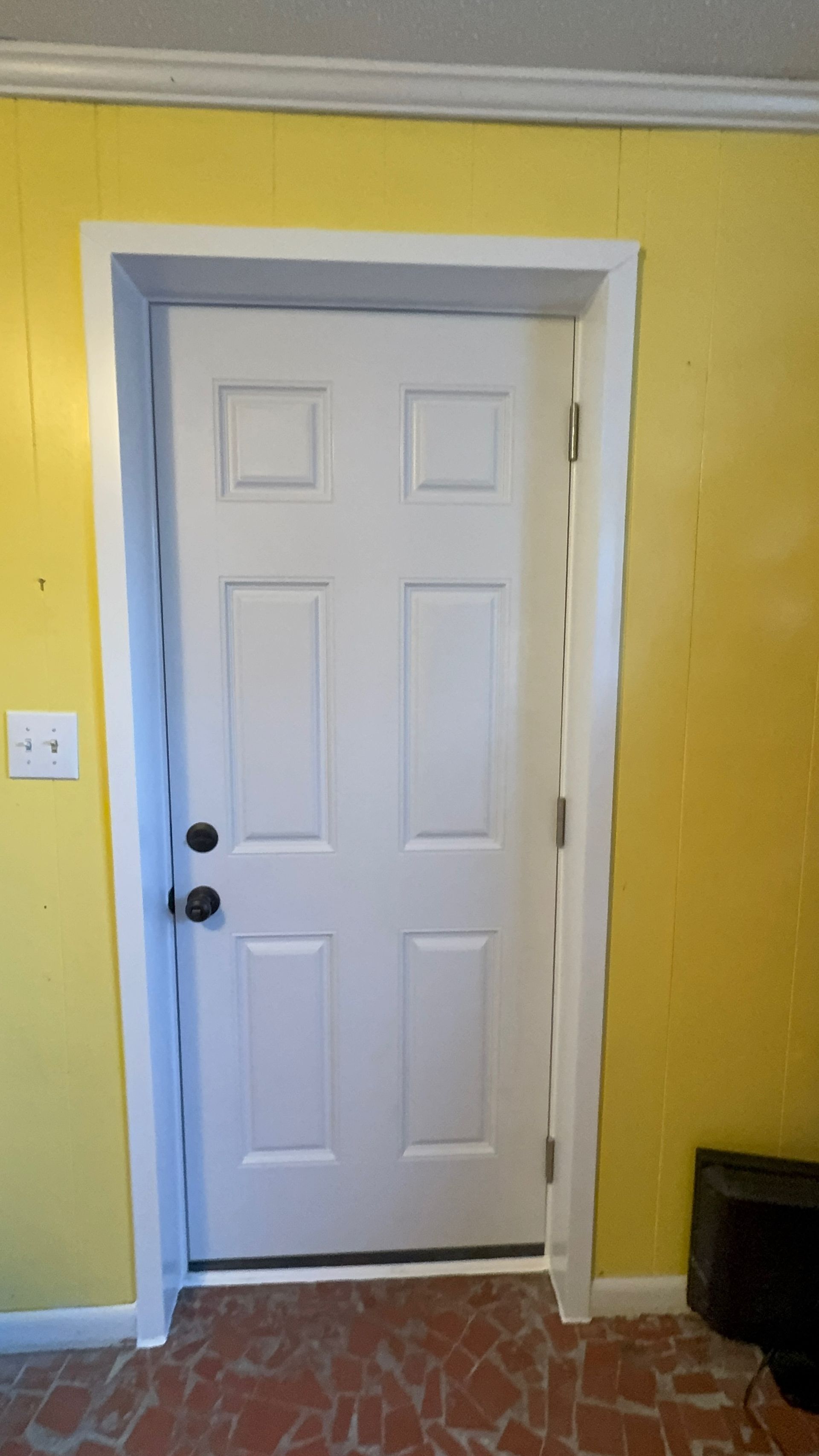 A white door is in a room with yellow walls.