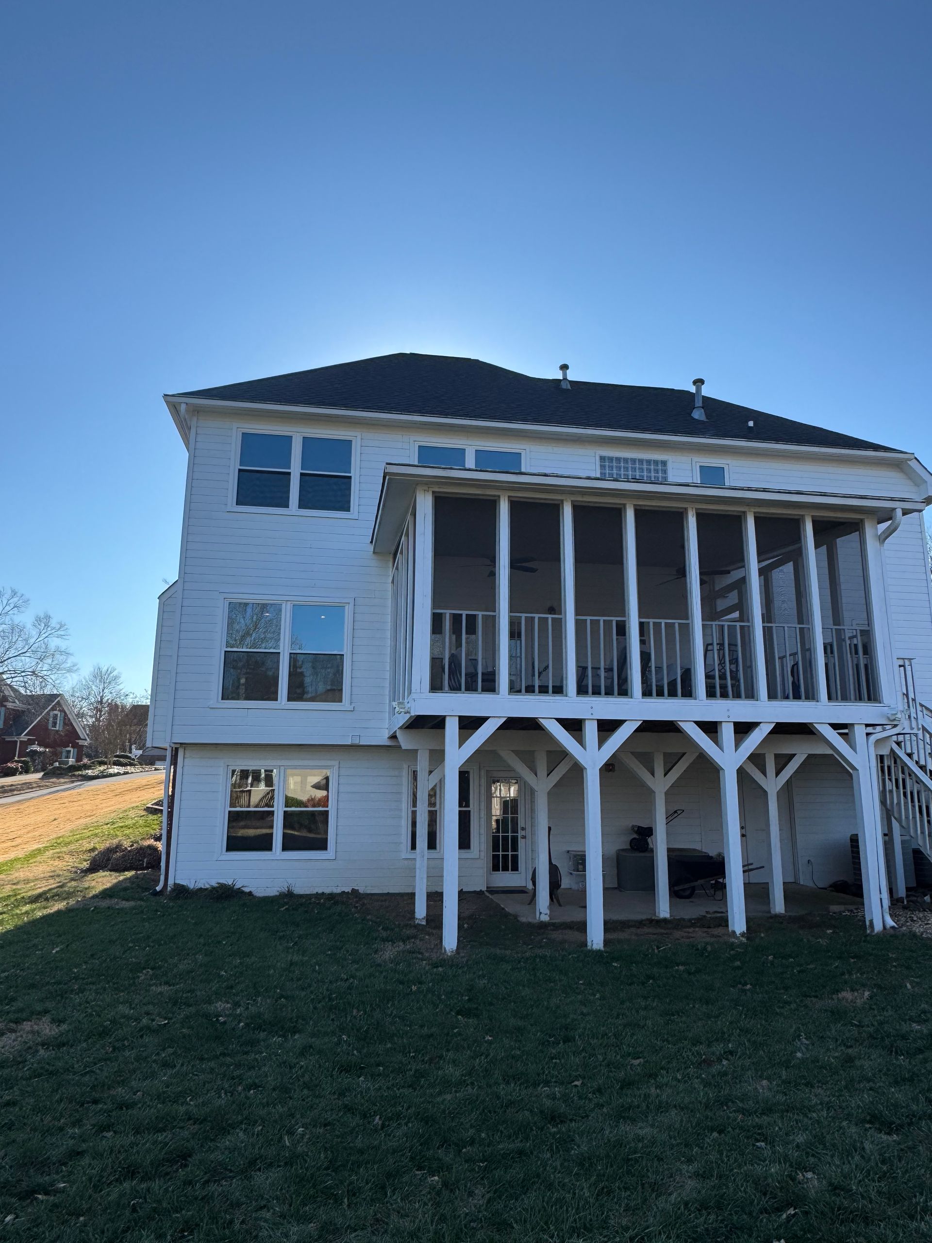 The back of a large white house with a screened in porch.