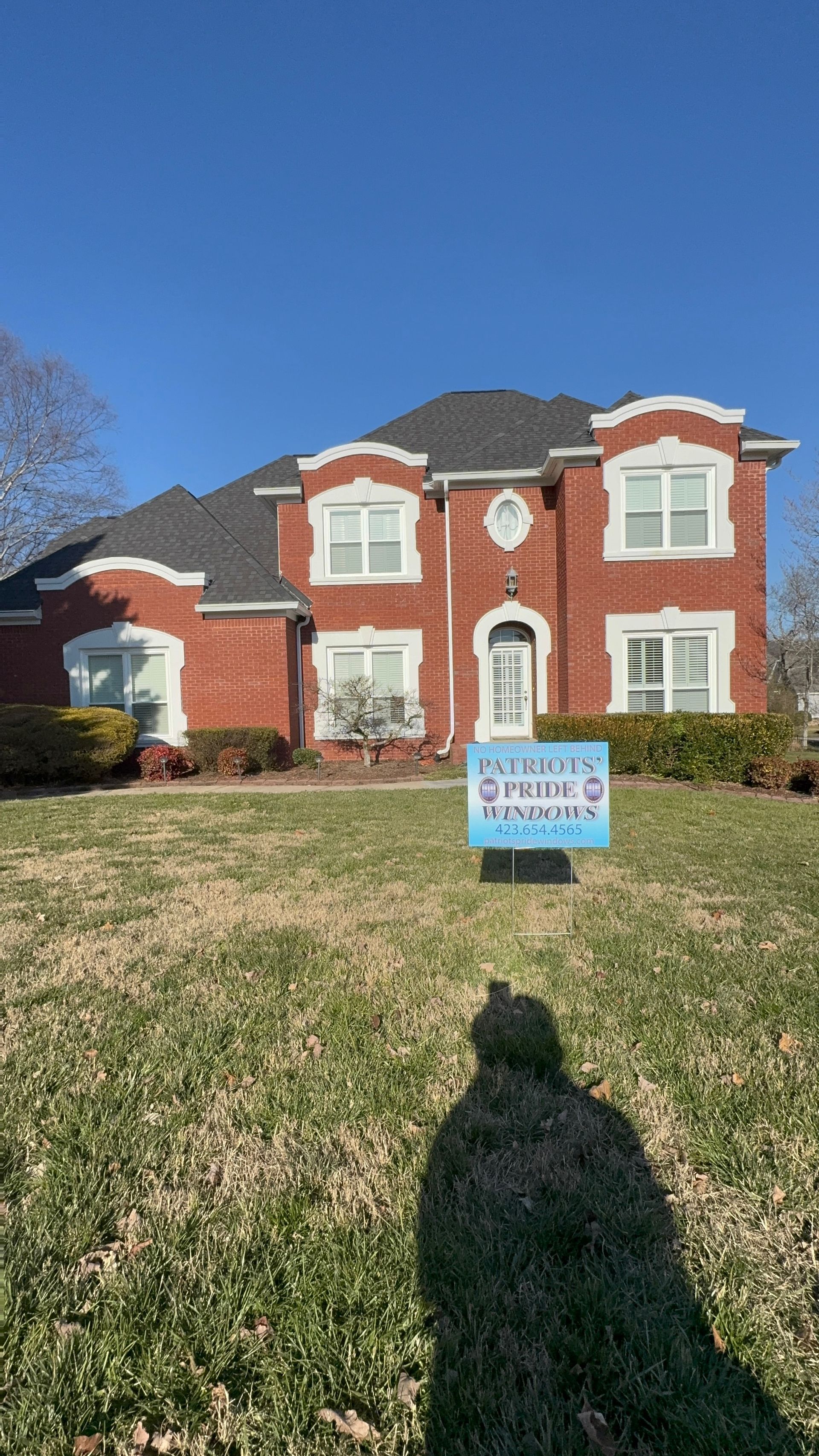 A large red brick house with a blue sign in front of it.