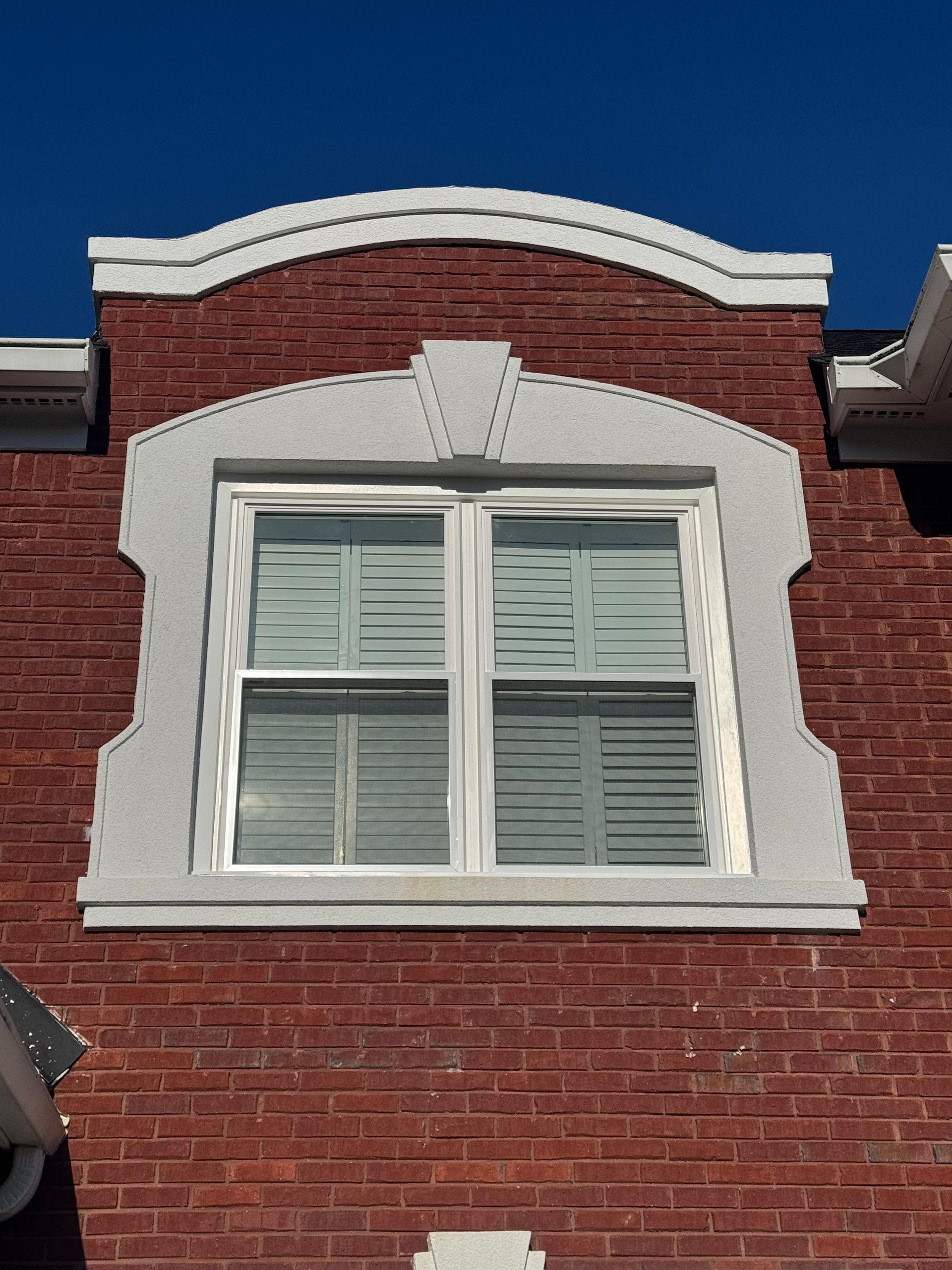 A brick building with a window and shutters on it