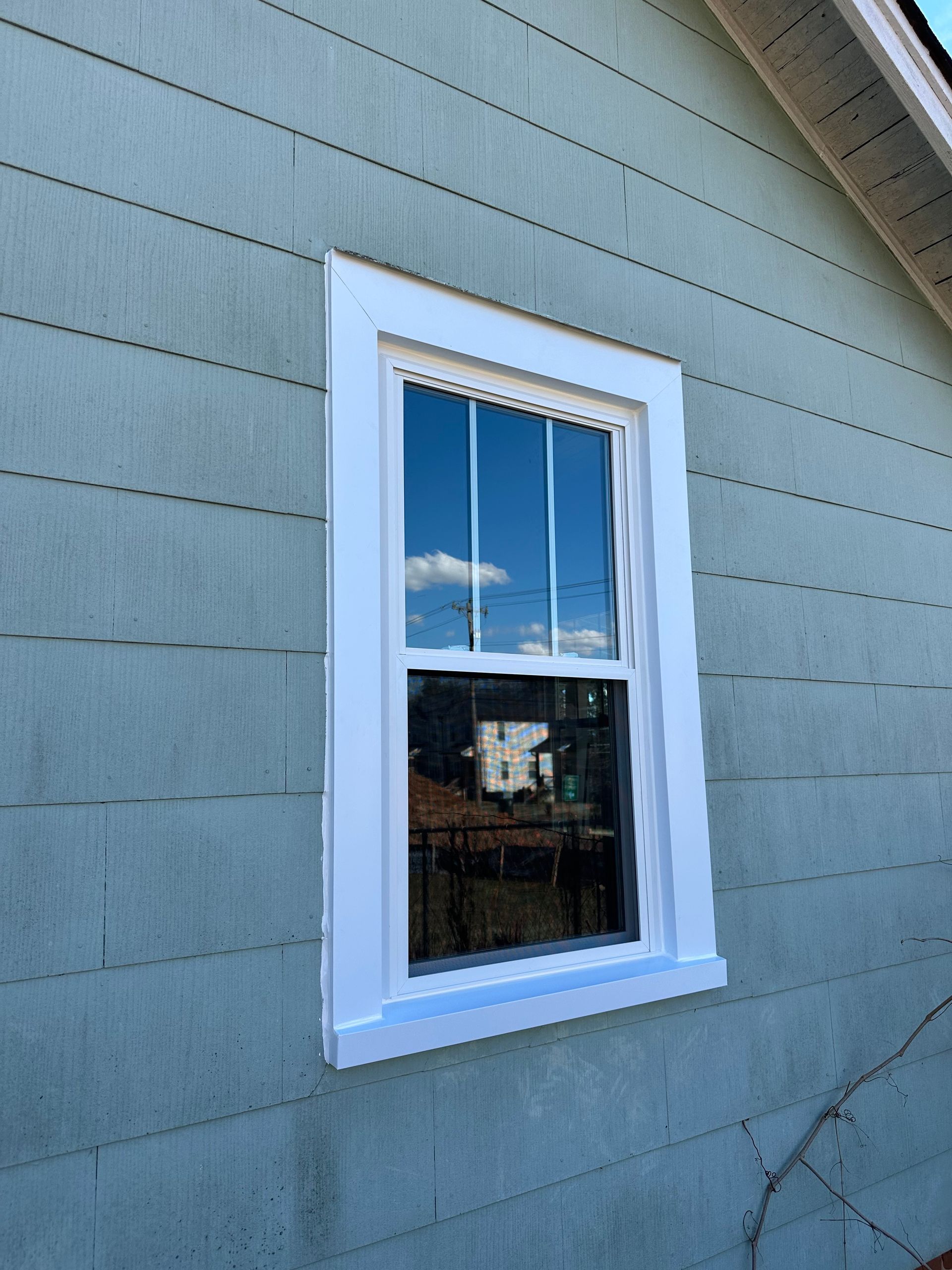 A window on the side of a house with a white frame