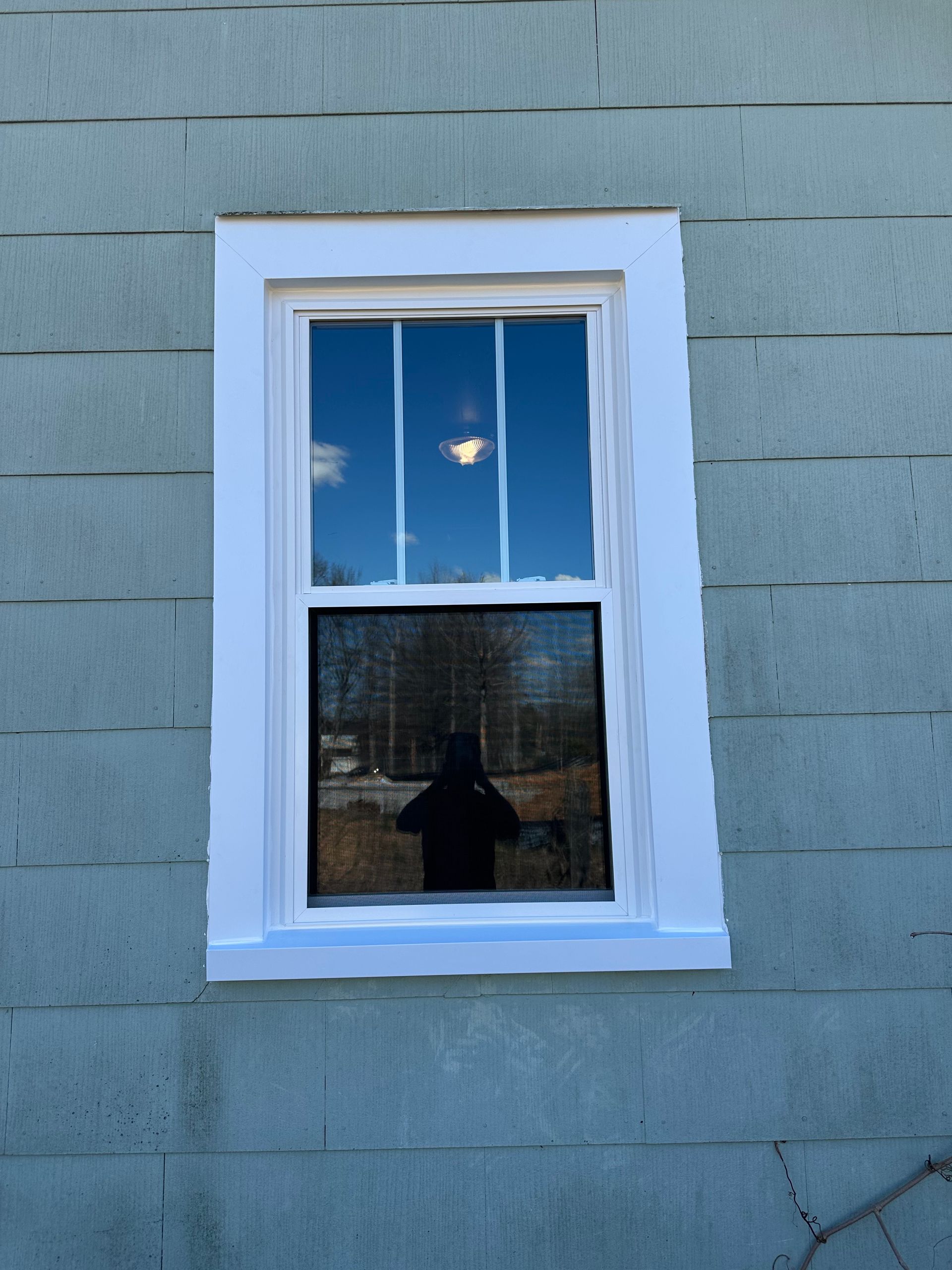 A window on the side of a house with a blue sky behind it
