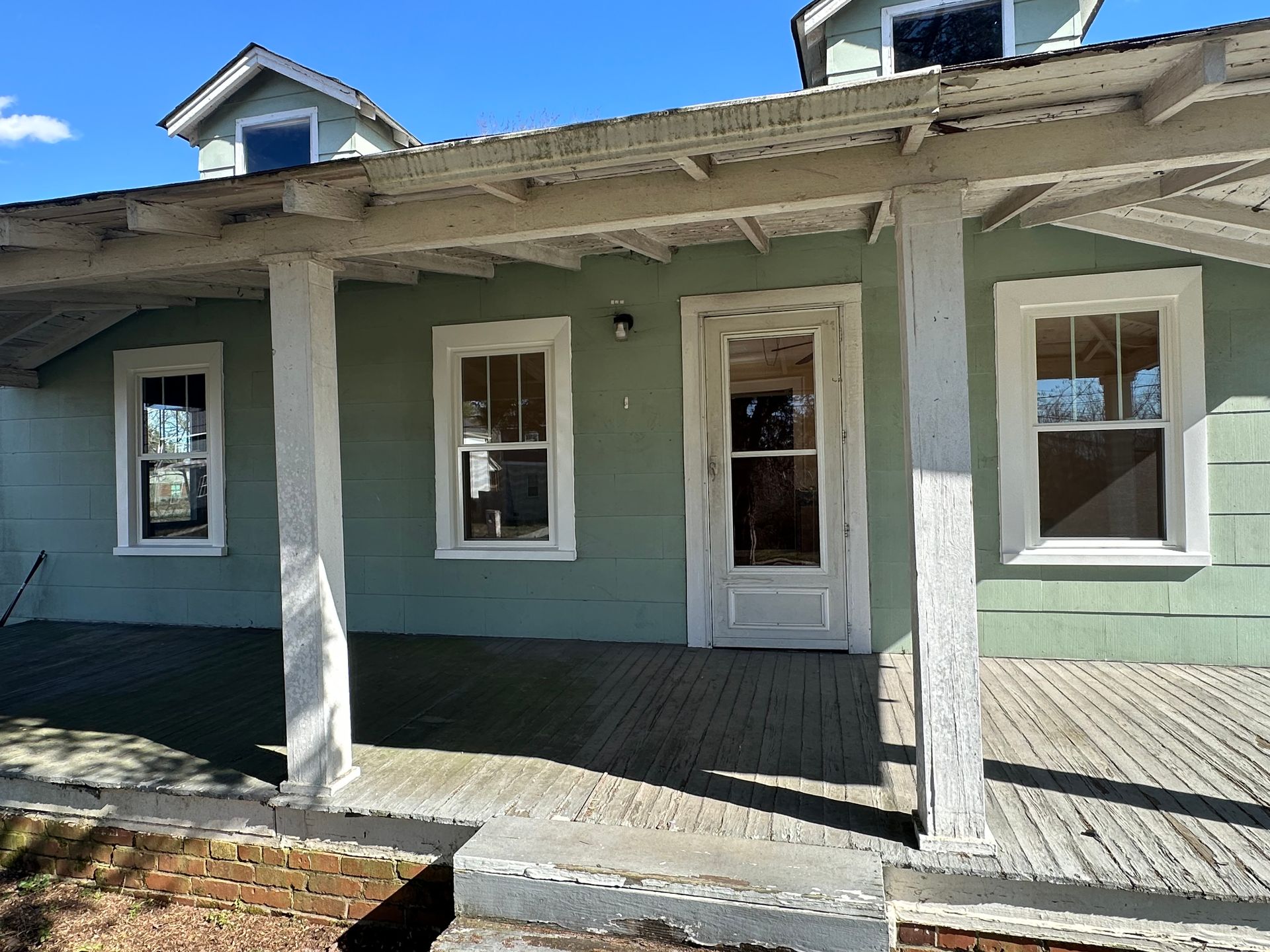 A green house with white trim and a porch