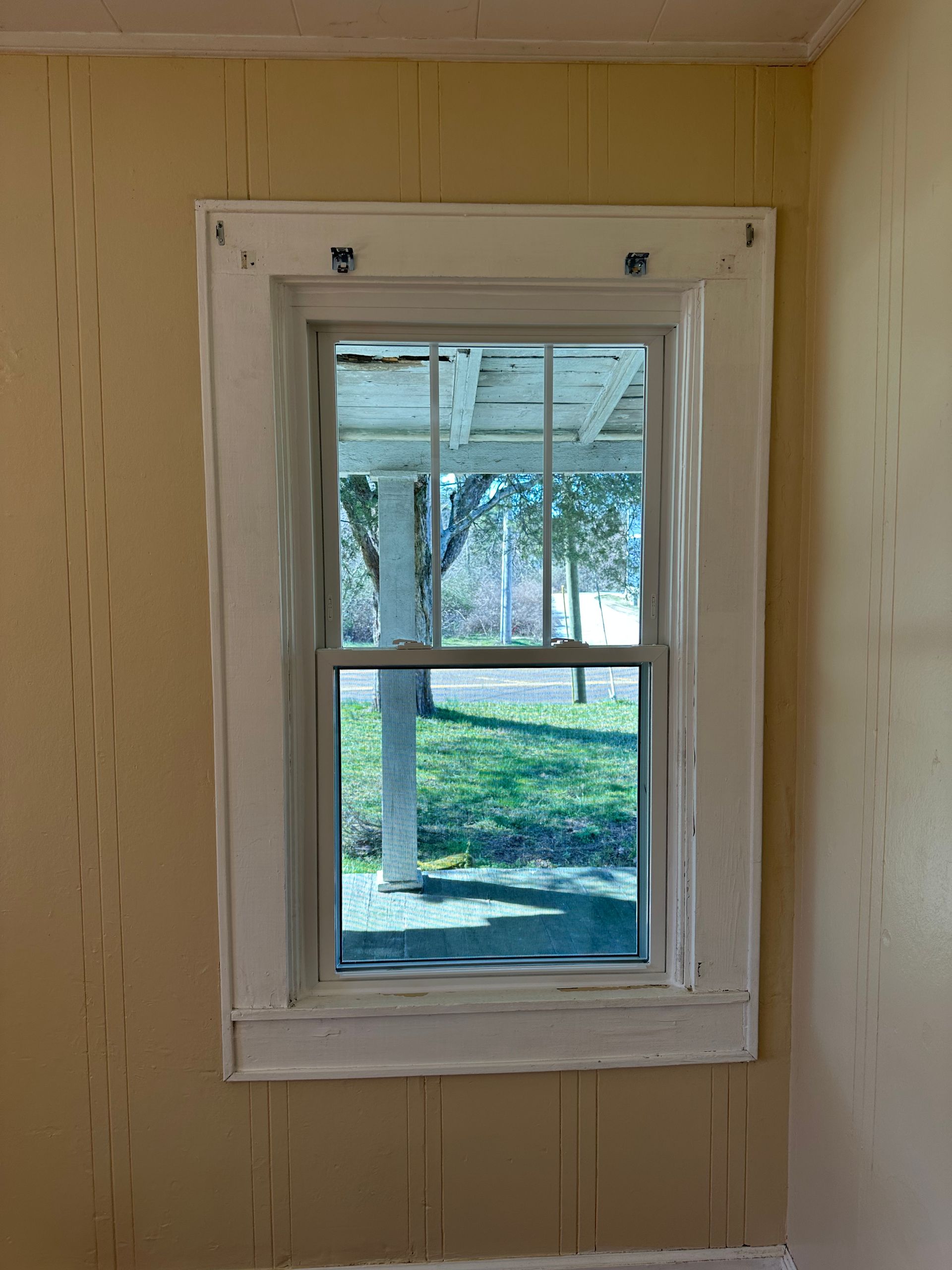 A window in a room with a view of a porch.