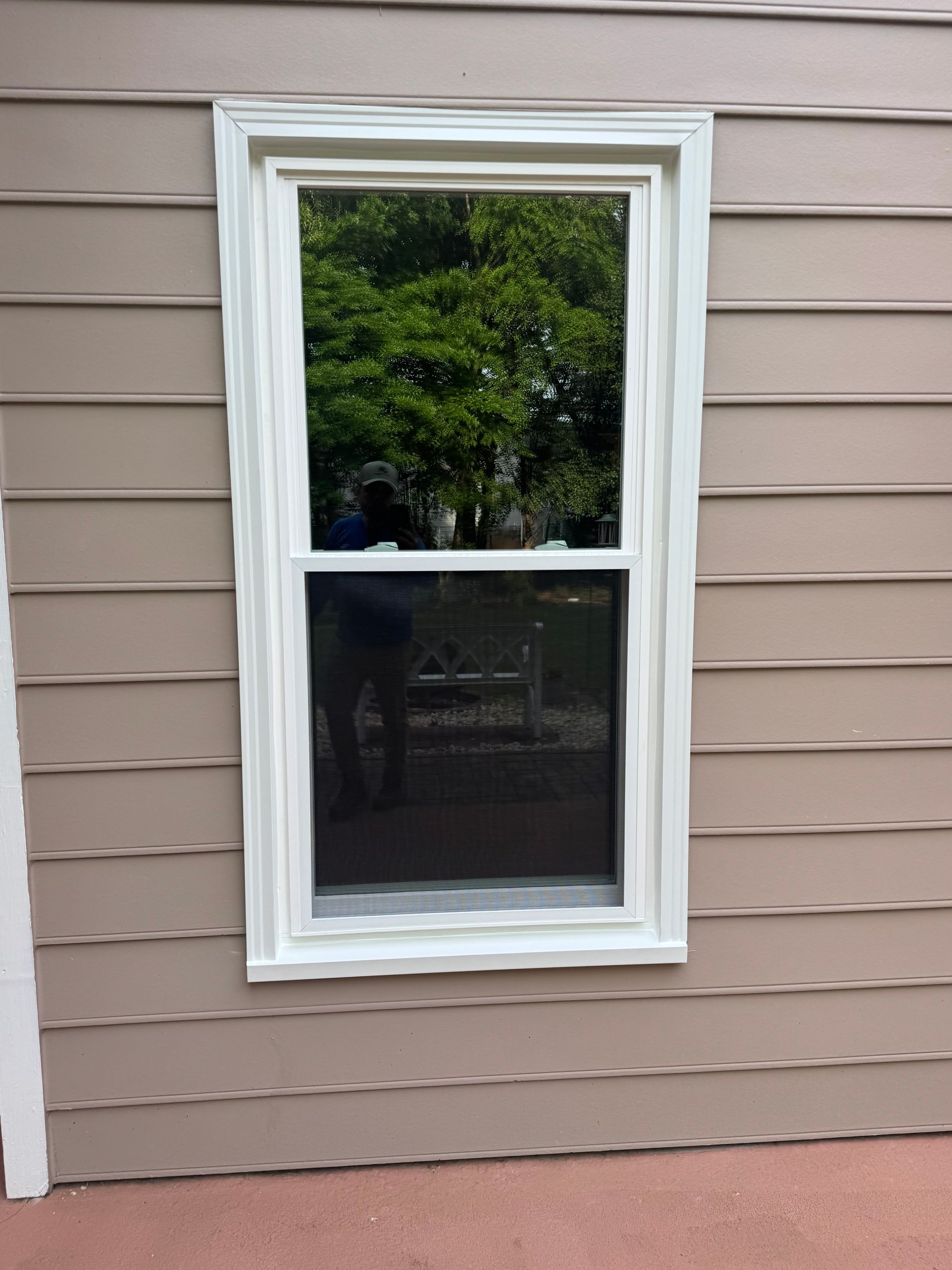A window with a white frame is on the side of a house.
