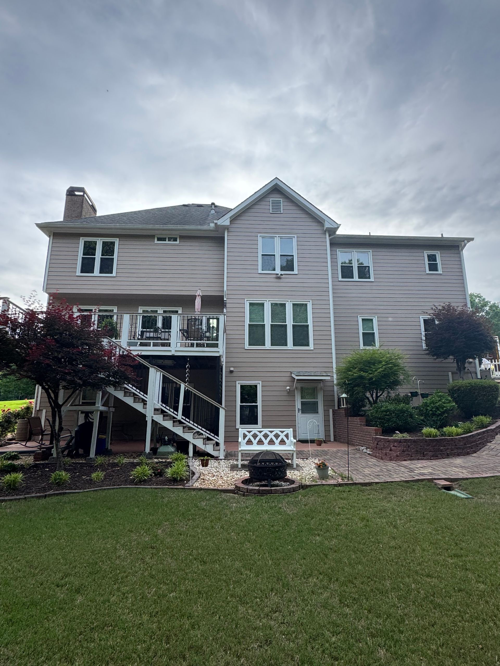 The back of a large house with a large lawn in front of it.