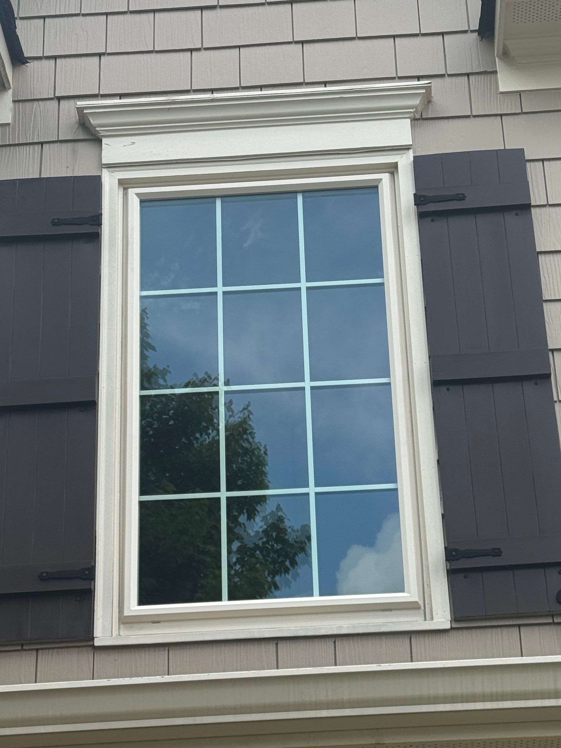 A window with black shutters on a brick building