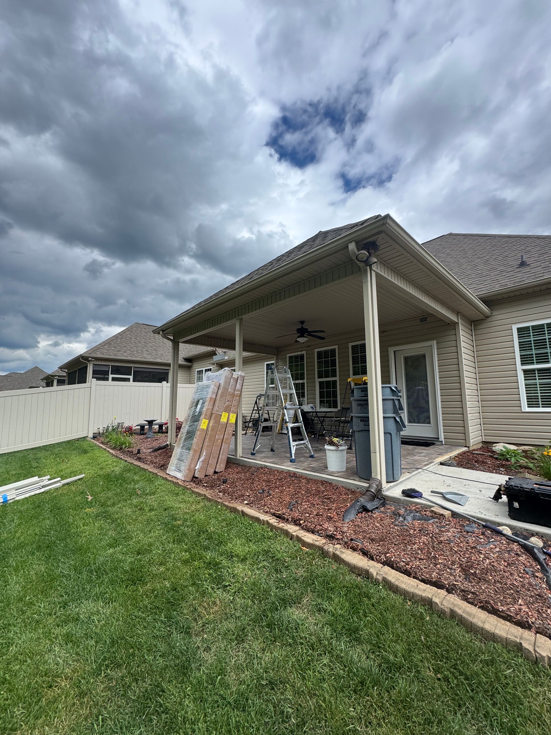 A house with a covered patio in the backyard is being painted.