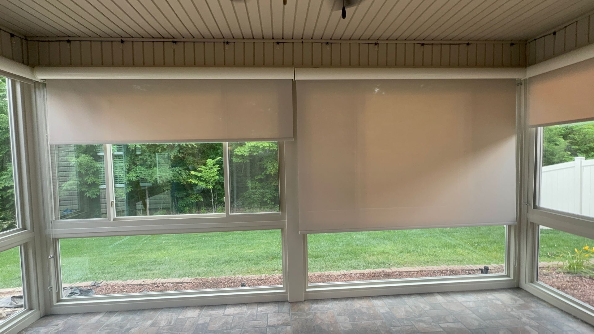 A screened in porch with a lot of windows and blinds.