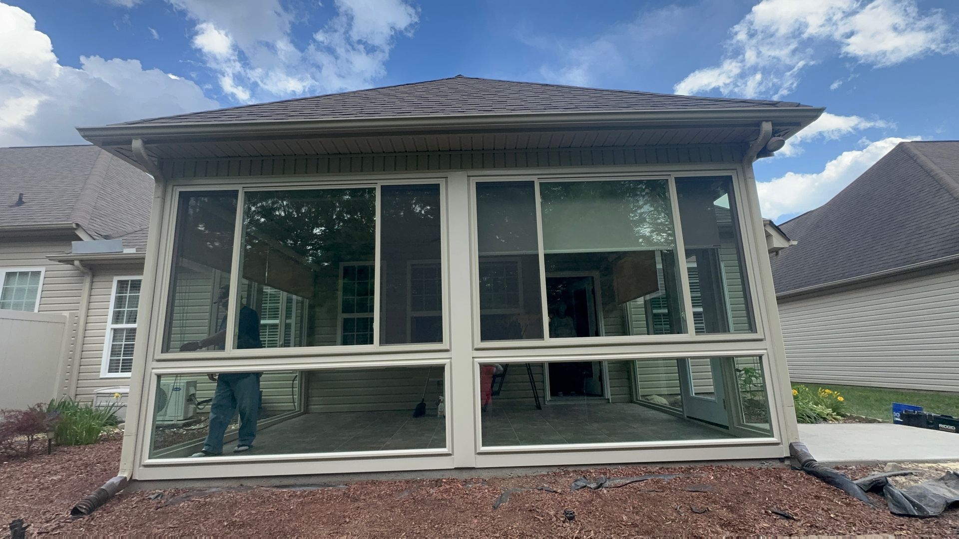 A screened in porch with a lot of windows and a roof.