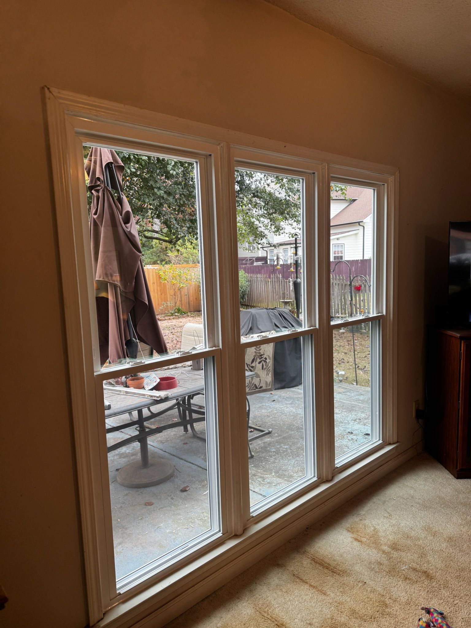 A living room with three windows looking out to a patio.