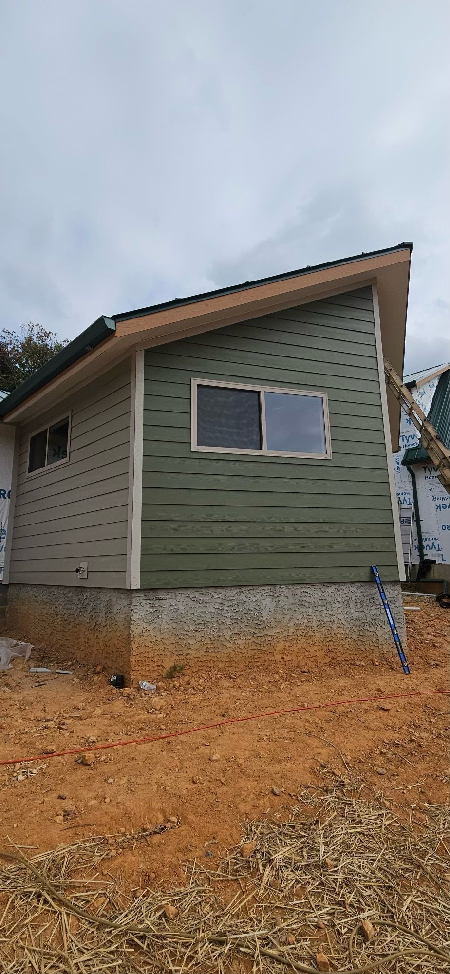 A small house is being built in the middle of a dirt field.