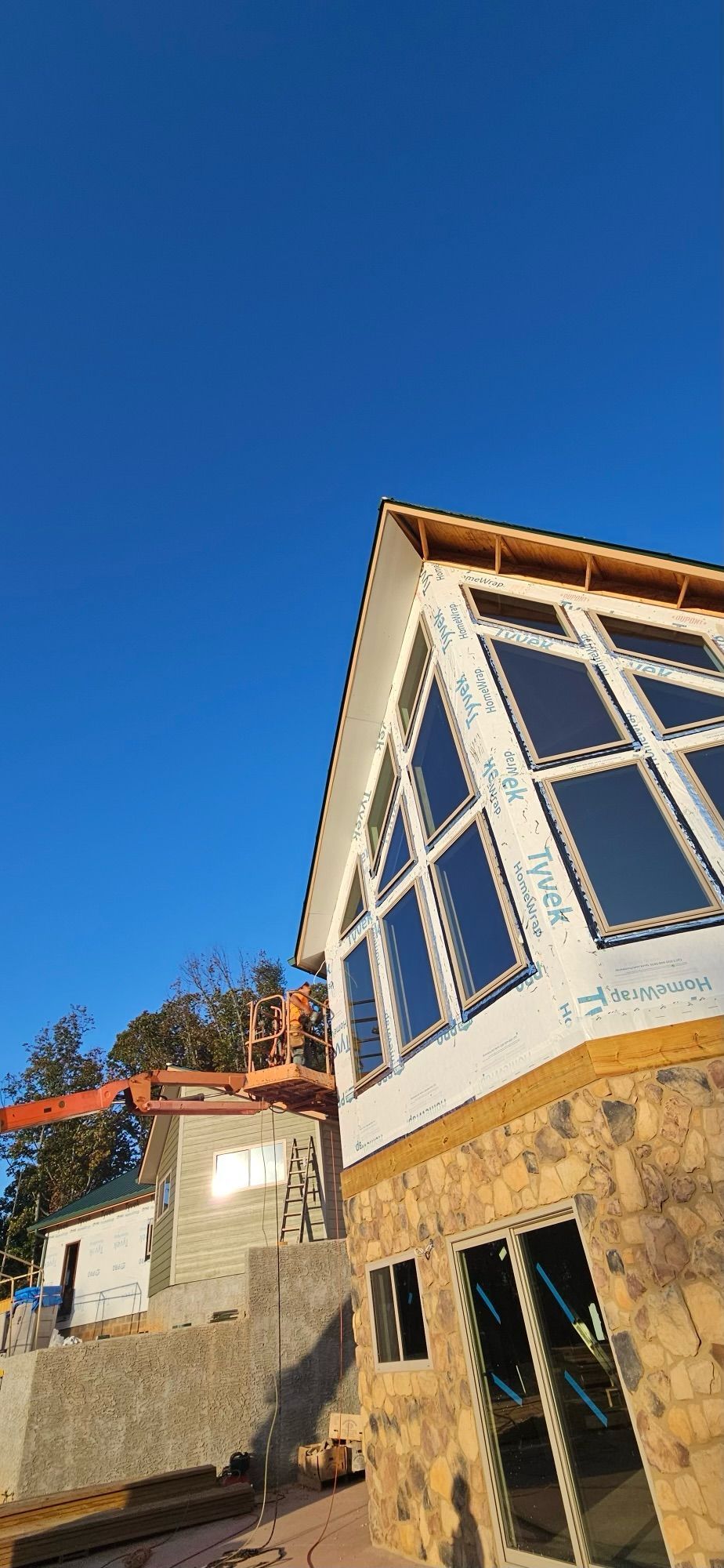 A house is being built with a lot of windows and a blue sky in the background.