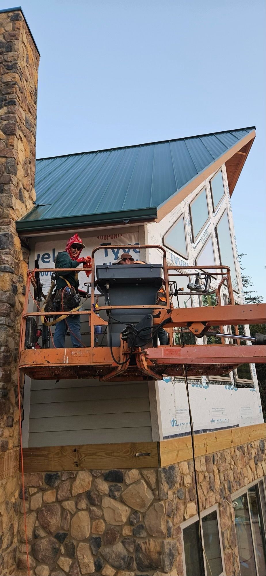 A group of men are working on a house with a green roof.