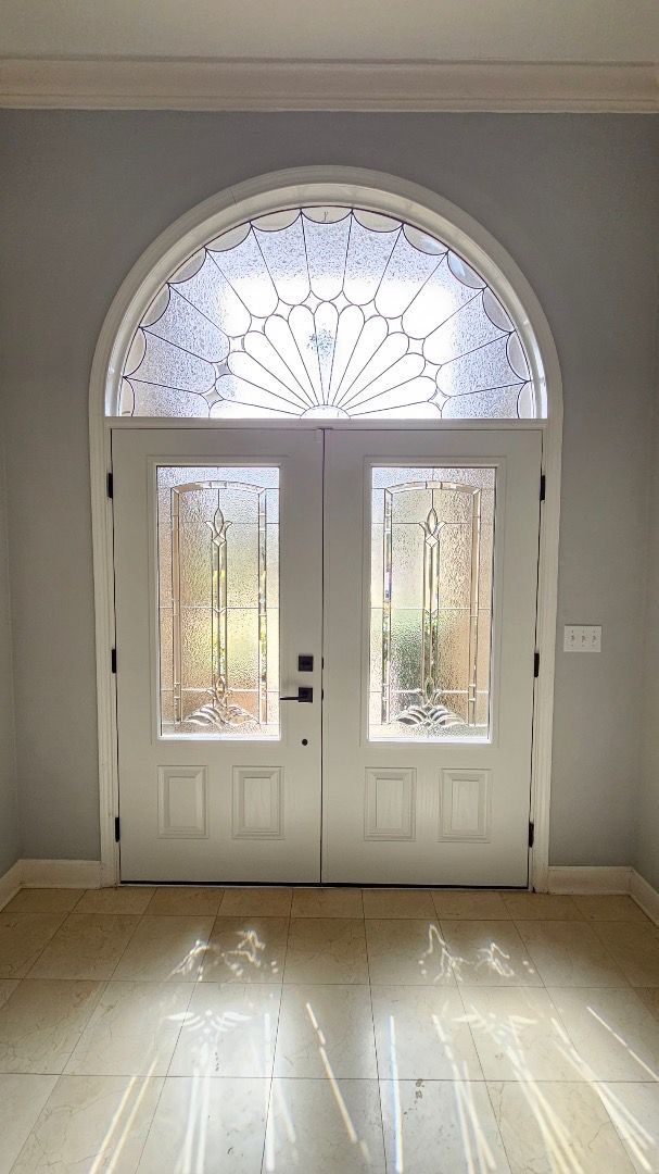 An empty room with a white door and a stained glass window.