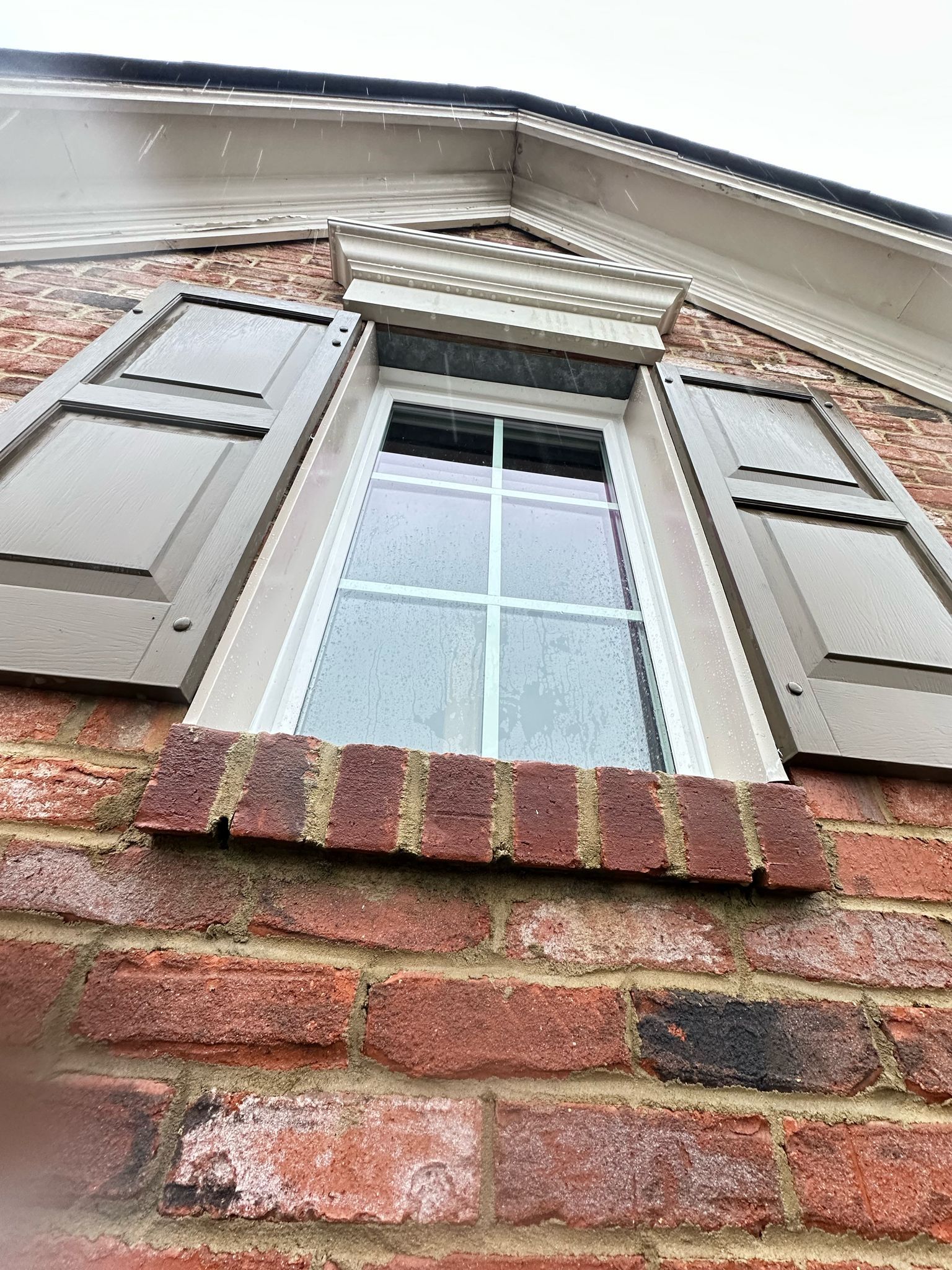 A brick building with a window and shutters on it.
