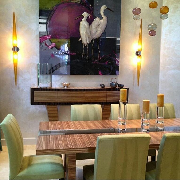 Dining room with a wooden table, green chairs, and artwork of white birds and a large purple shape.