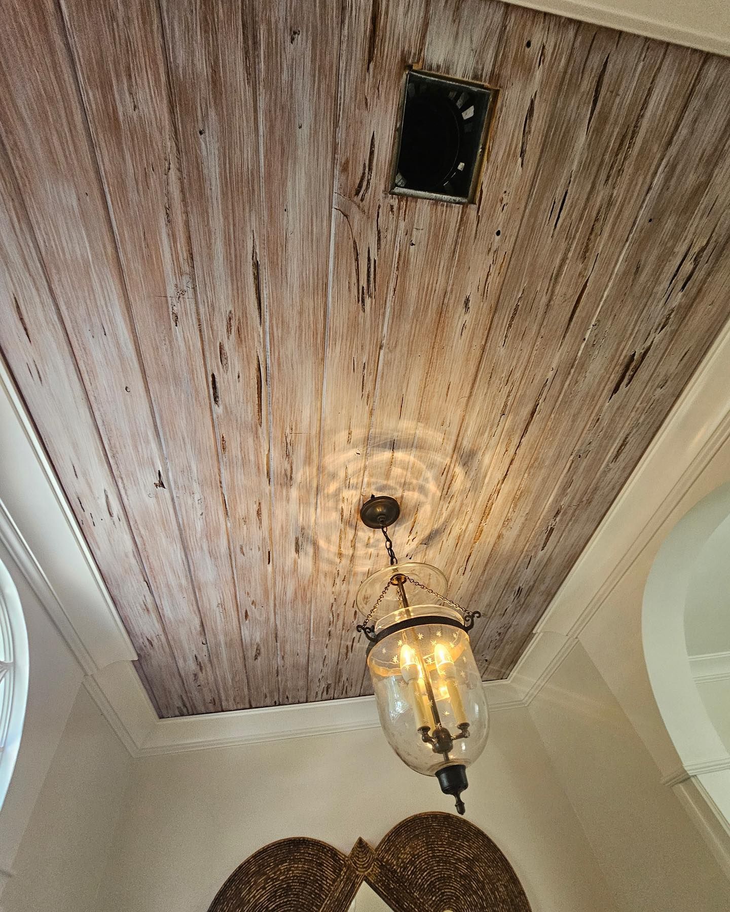 Whitewashed wood plank ceiling with a hanging lantern and vent.