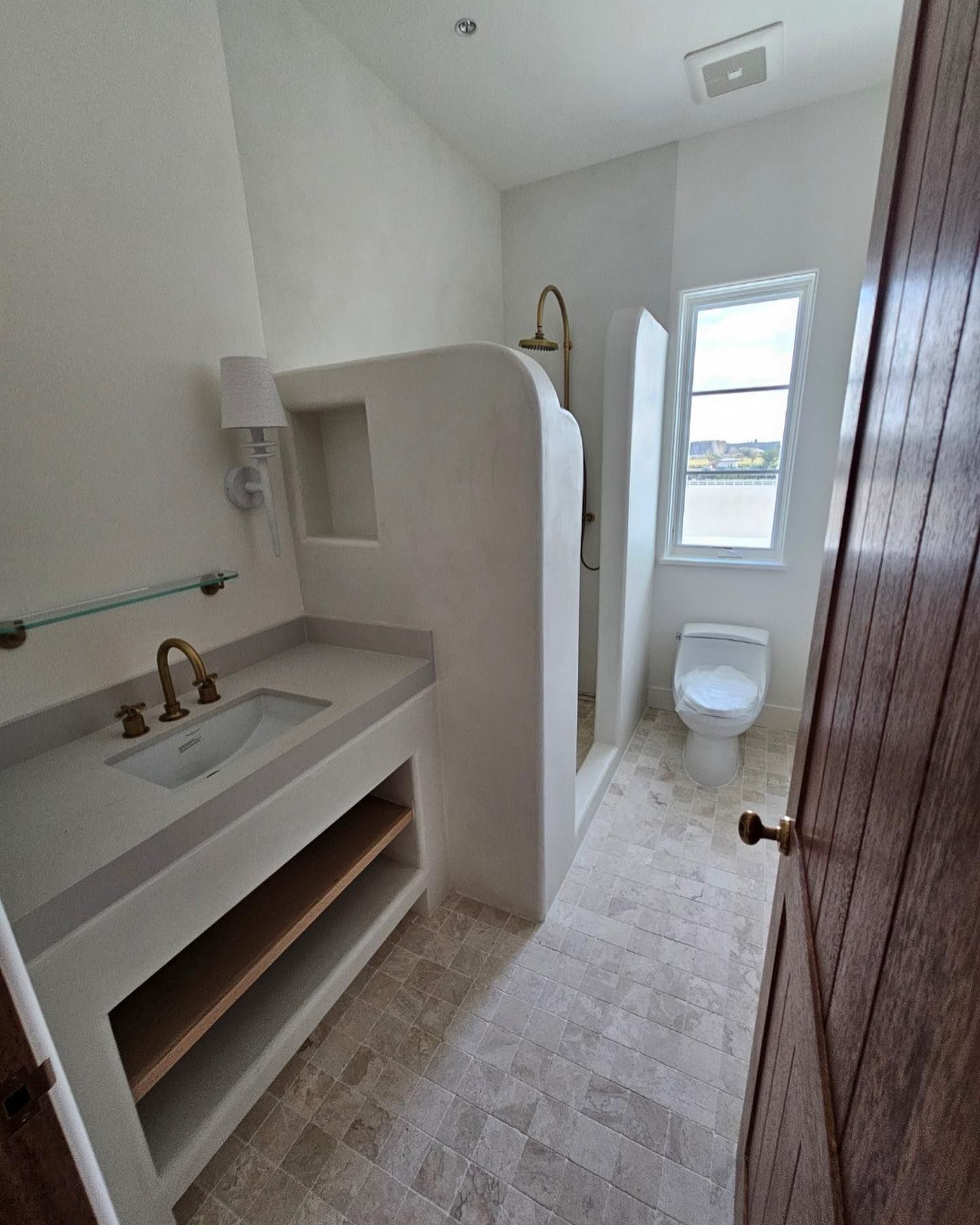 Bathroom with a white sink, shower stall, and toilet, with a partly open wooden door.