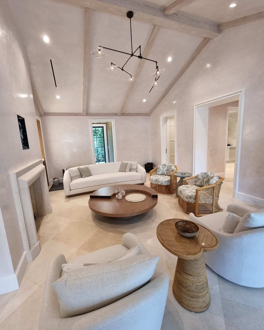 Spacious living room with cream-colored walls, light wood furniture, and a modern black chandelier.